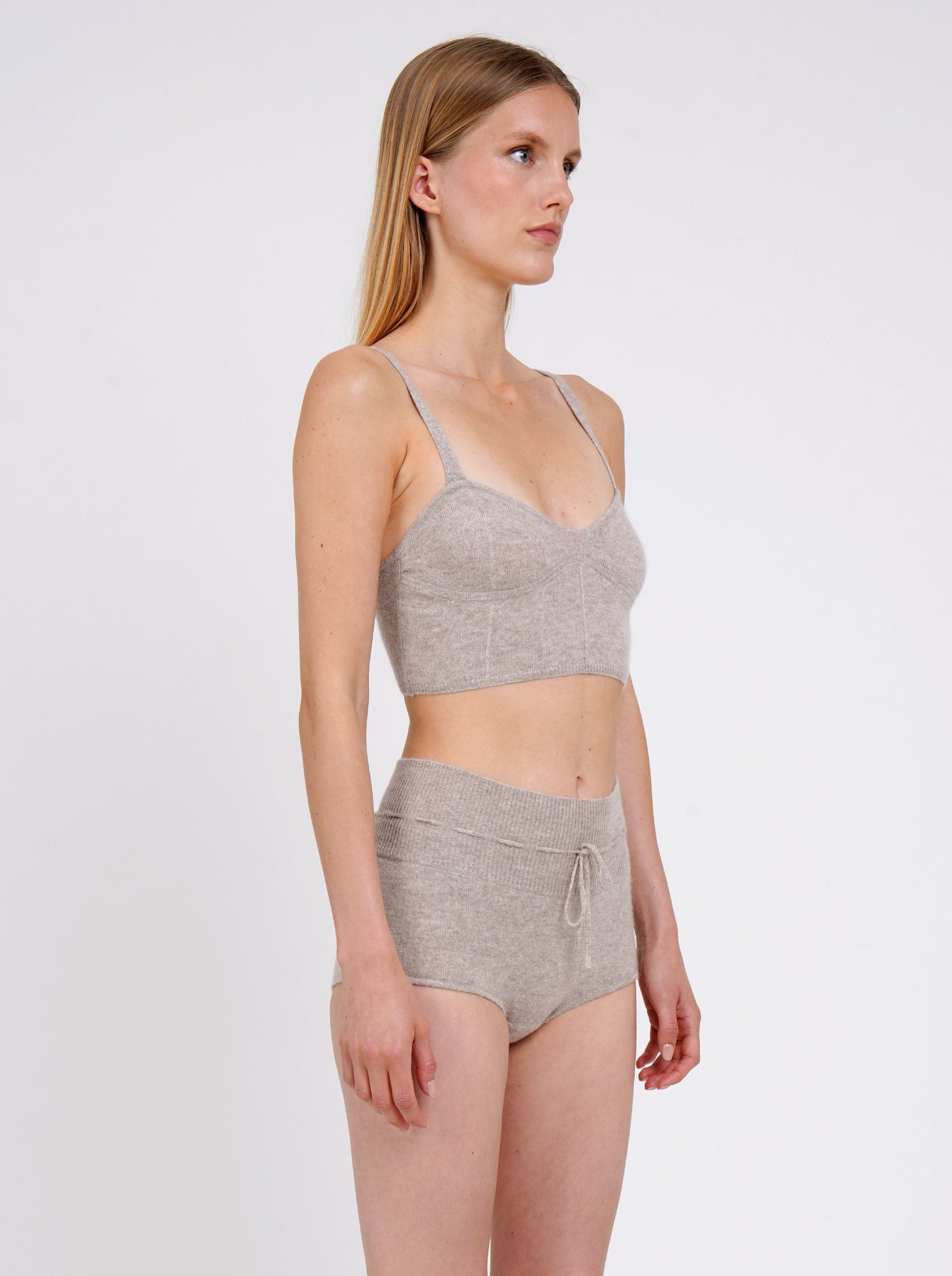 close-up side view model  in beige cashmere shorts with drawstring waist and matching cropped bra top 