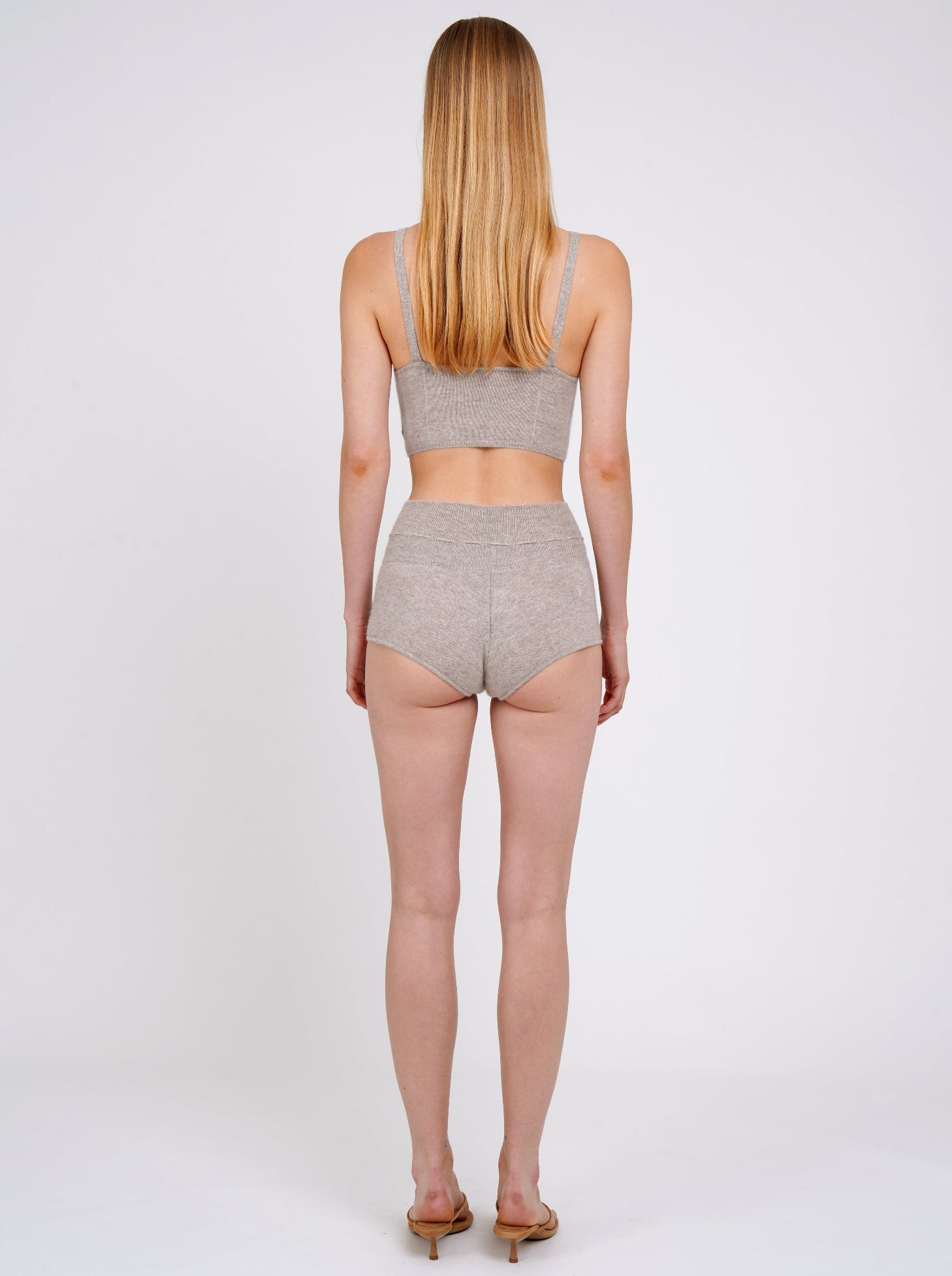 Back view standing model in beige cashmere shorts with and matching beige knit cropped bra top. 