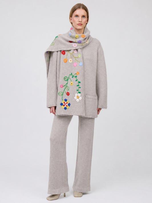 Front view model in pale beige knitted jacket with flower embroidered scarf and matching cashmere knit pants.