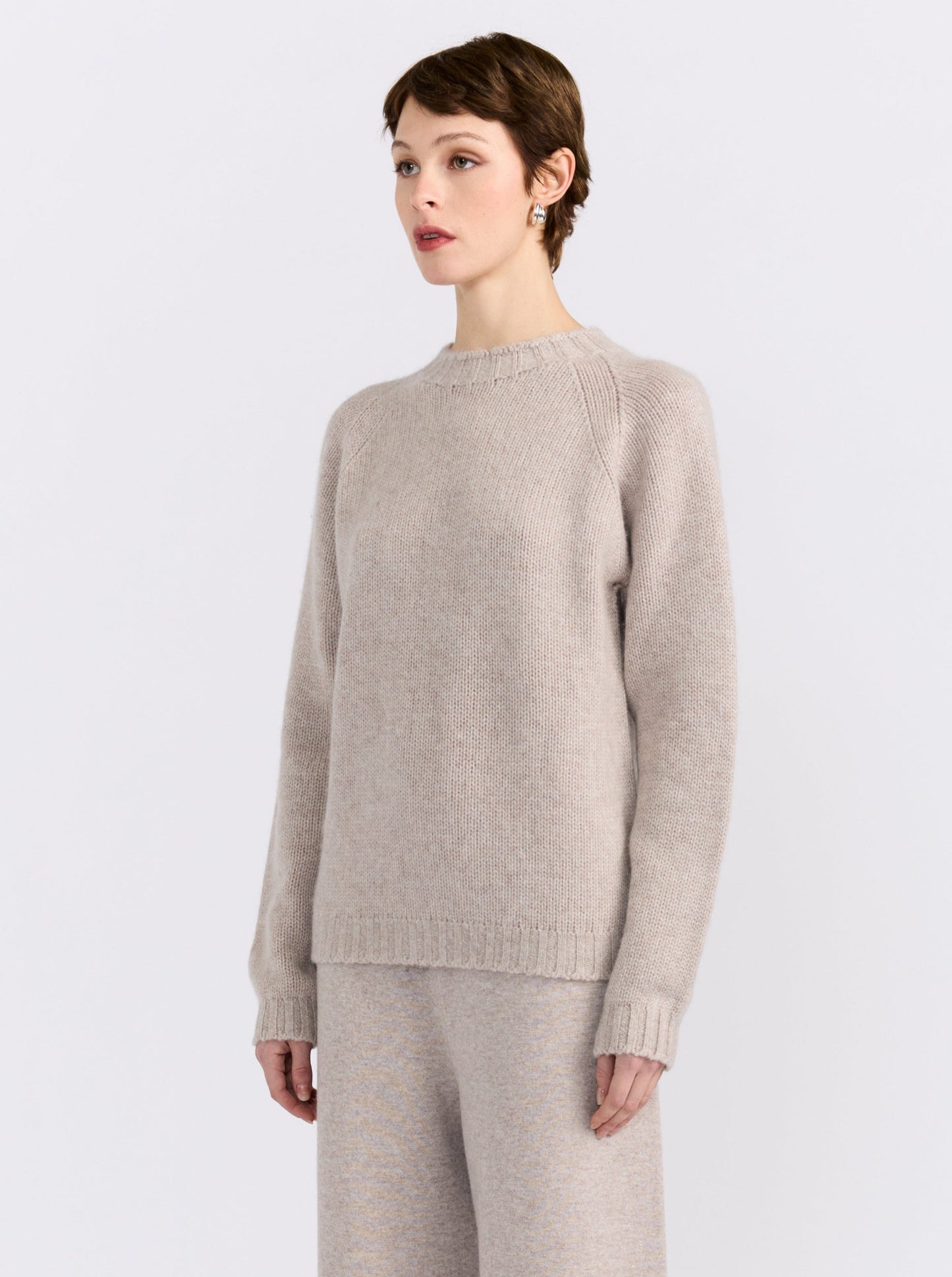 MANDKHAI new beige pure cashmere round neck sweater with raglan sleeves and a soft mink finish, styled with matching cashmere trousers.