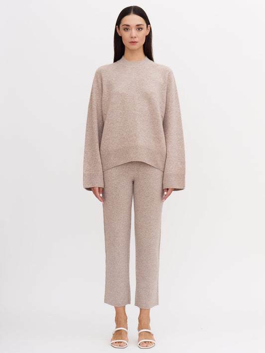 Front view of model wearing beige cashmere outfit: cropped cashmere suit pants and matching cashmere mock neck jumper.