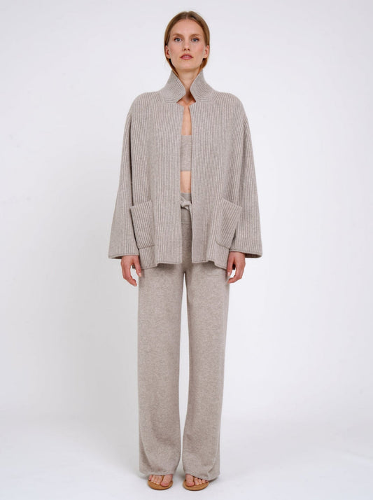 Front view model wearing beige ribbed knit cashmere jacket with high collar and patch pockets; worn with beige cashmere top and pants.