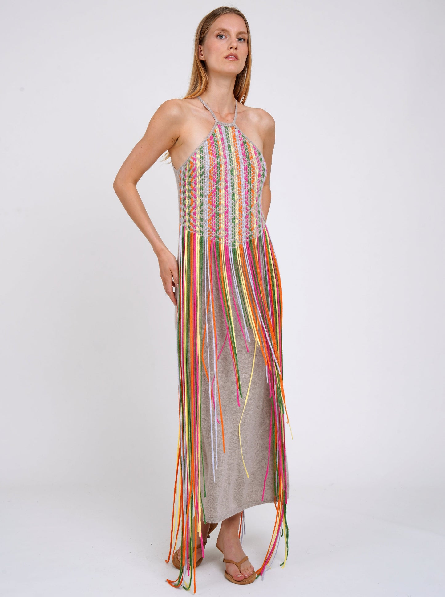 model wears summer weight cashmere shift dress with thin halterneck straps and decorated with coloured fringes which flow to the ground.