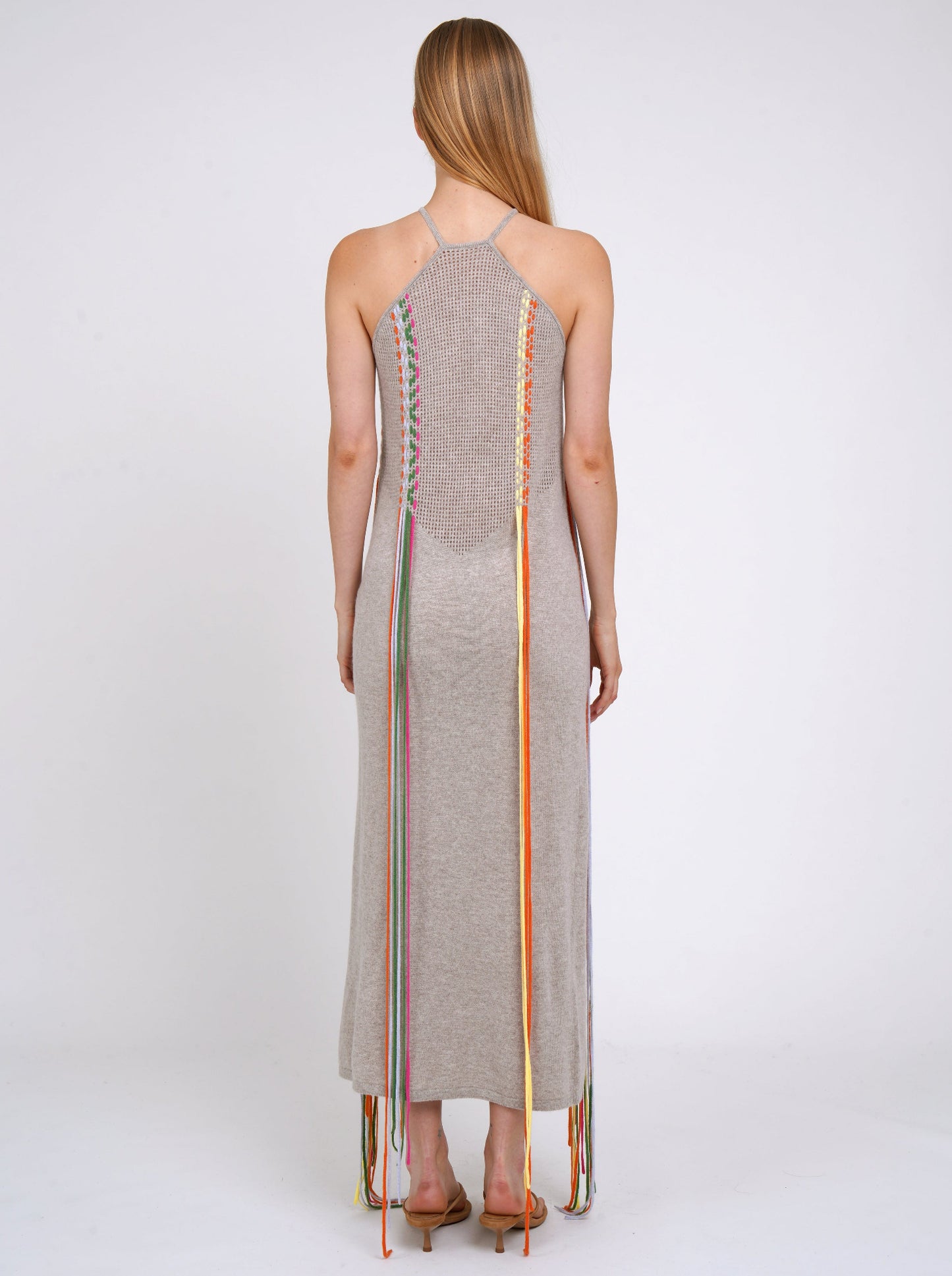Back view light weight cashmere shift dress with thin halterneck straps and decorated with coloured fringes which flow to the ground.