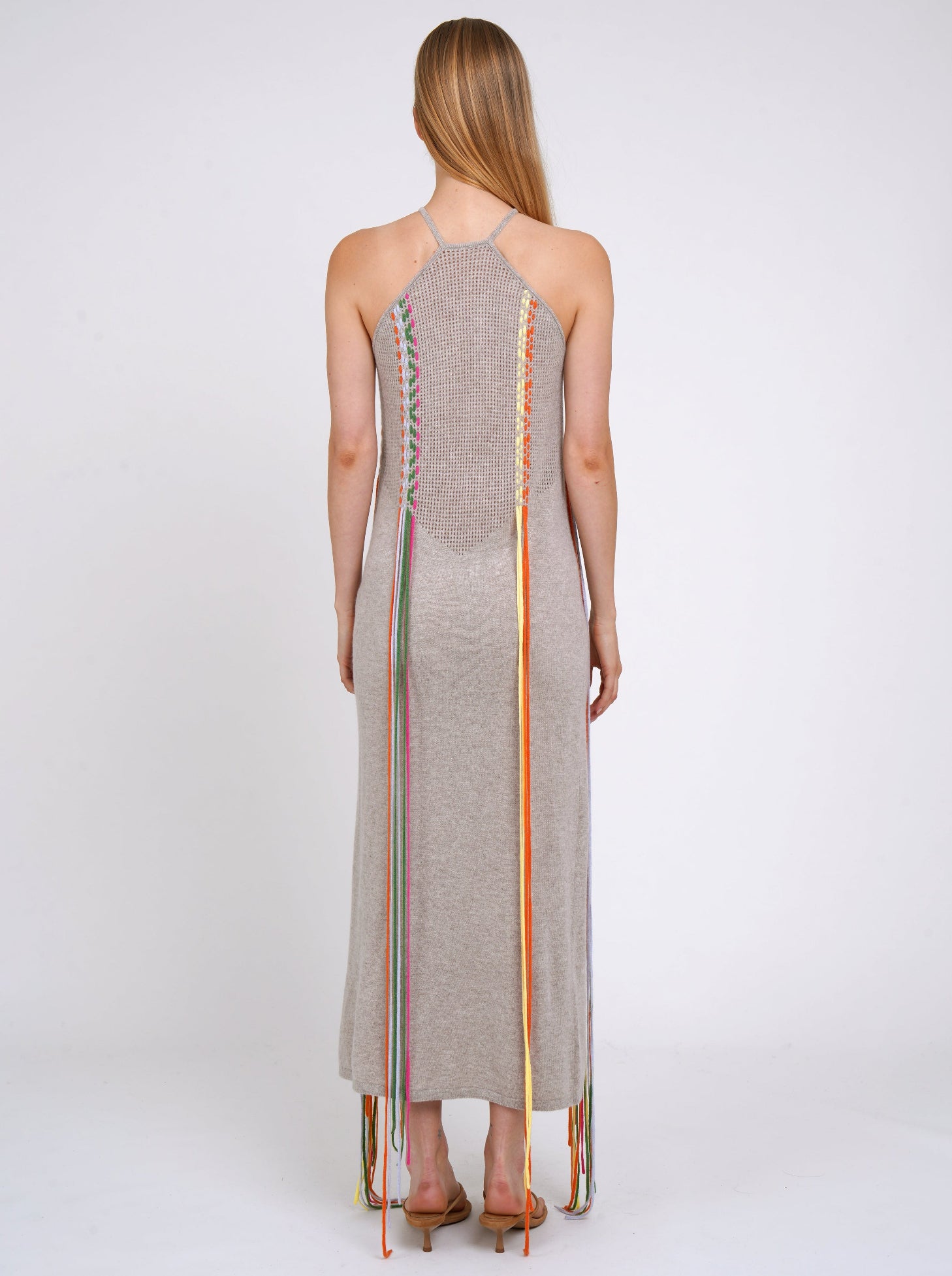 Back view light weight cashmere shift dress with thin halterneck straps and decorated with coloured fringes which flow to the ground.