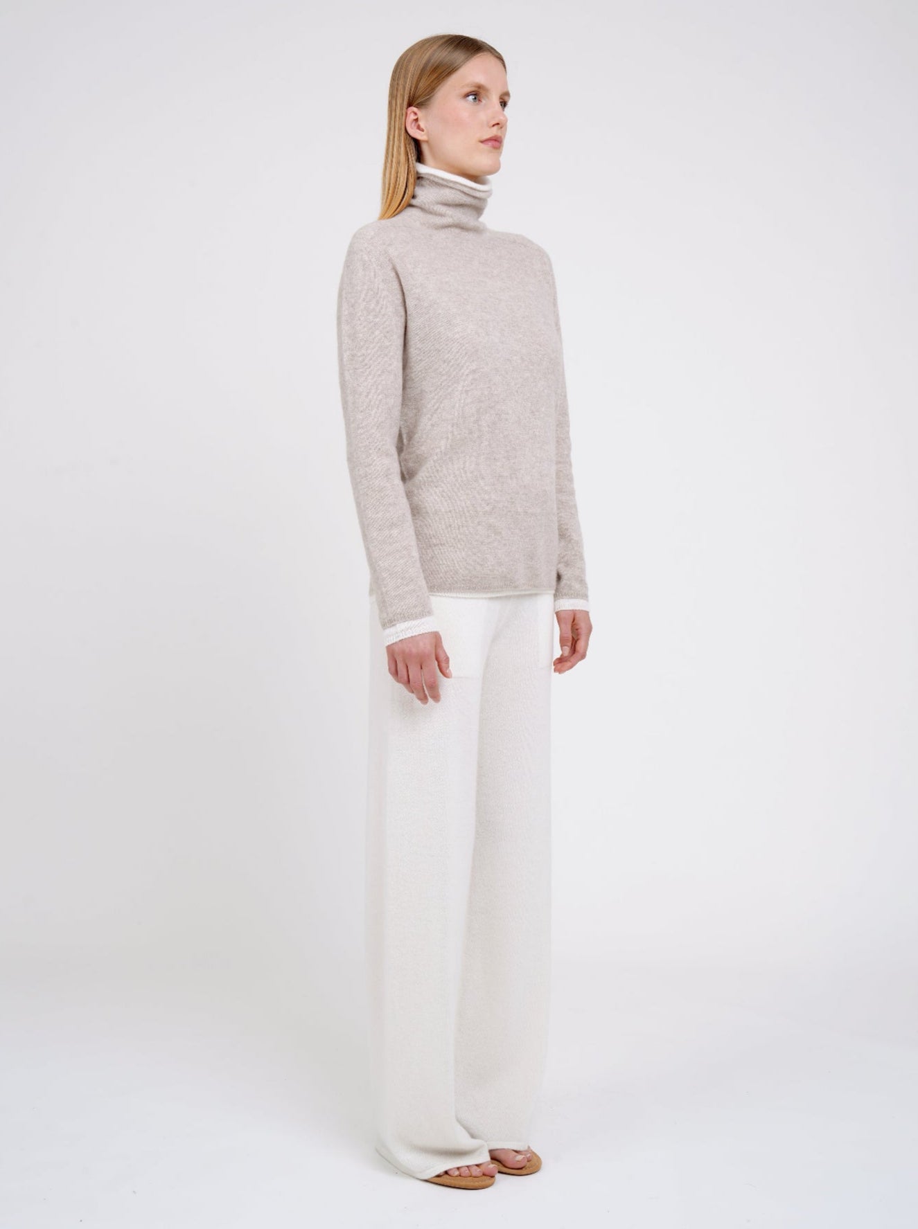 Side view Model wearing double set of white and beige roll neck cashmere jumper.