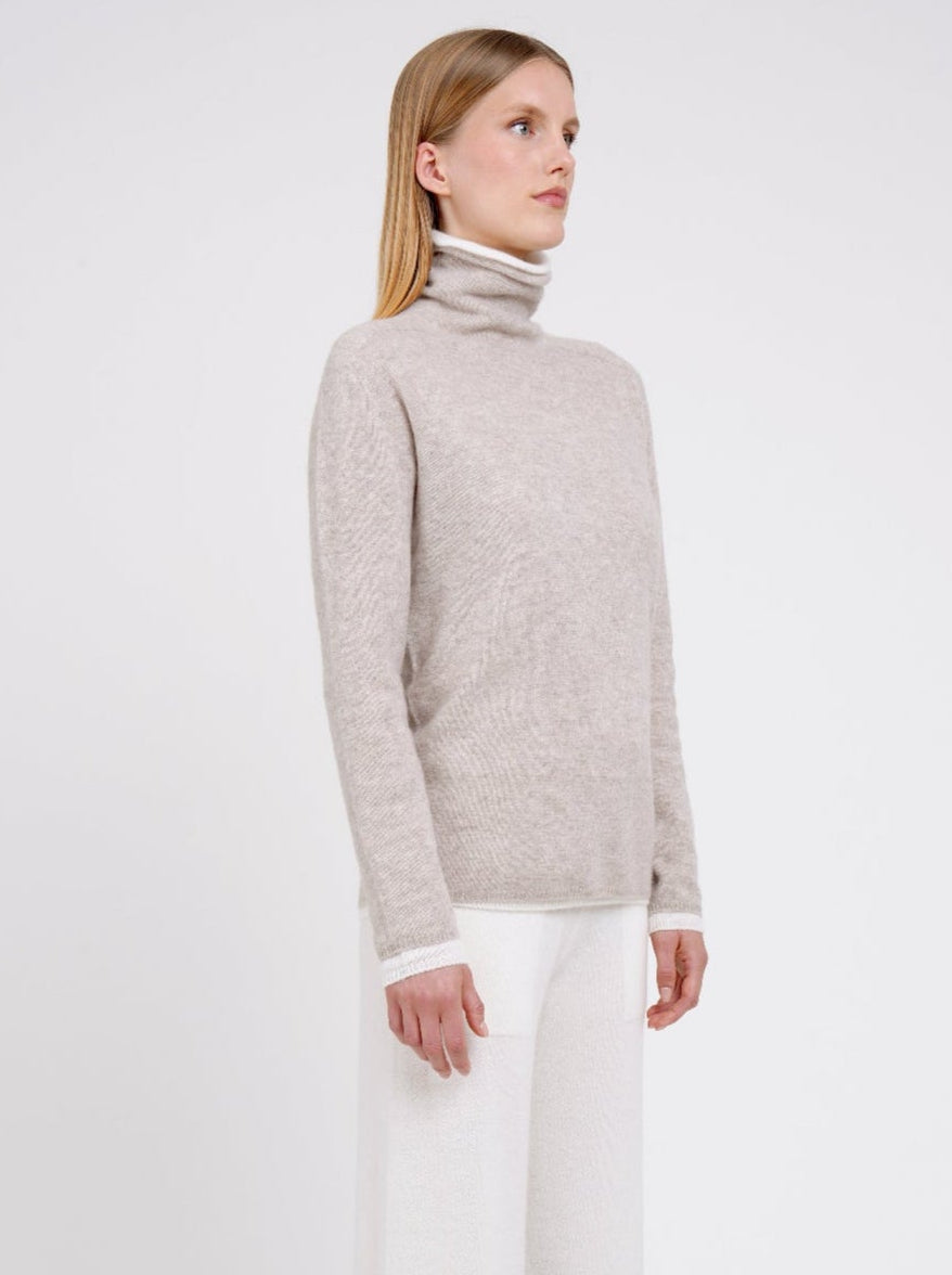 Side view Model wearing double set of white and beige roll neck cashmere jumper.