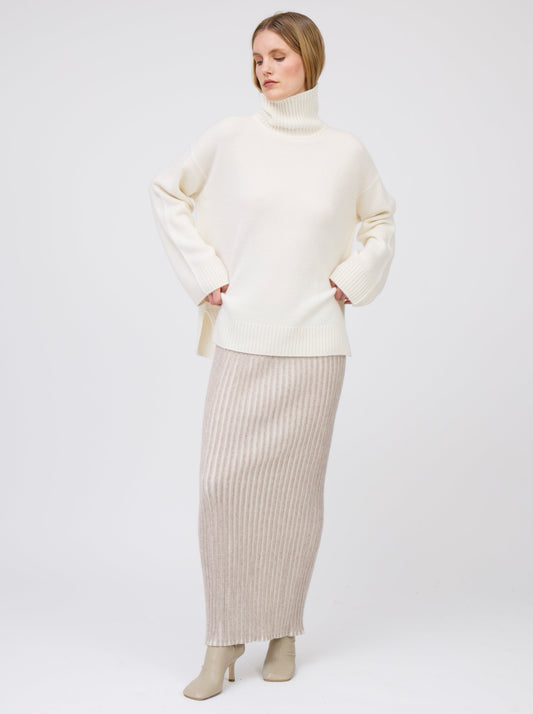 Front view model wears maxi length slim tube skirt in beige and white vertical stripes; worn with oversized natural white roll neck cashmere jumper and beige heeled boots.