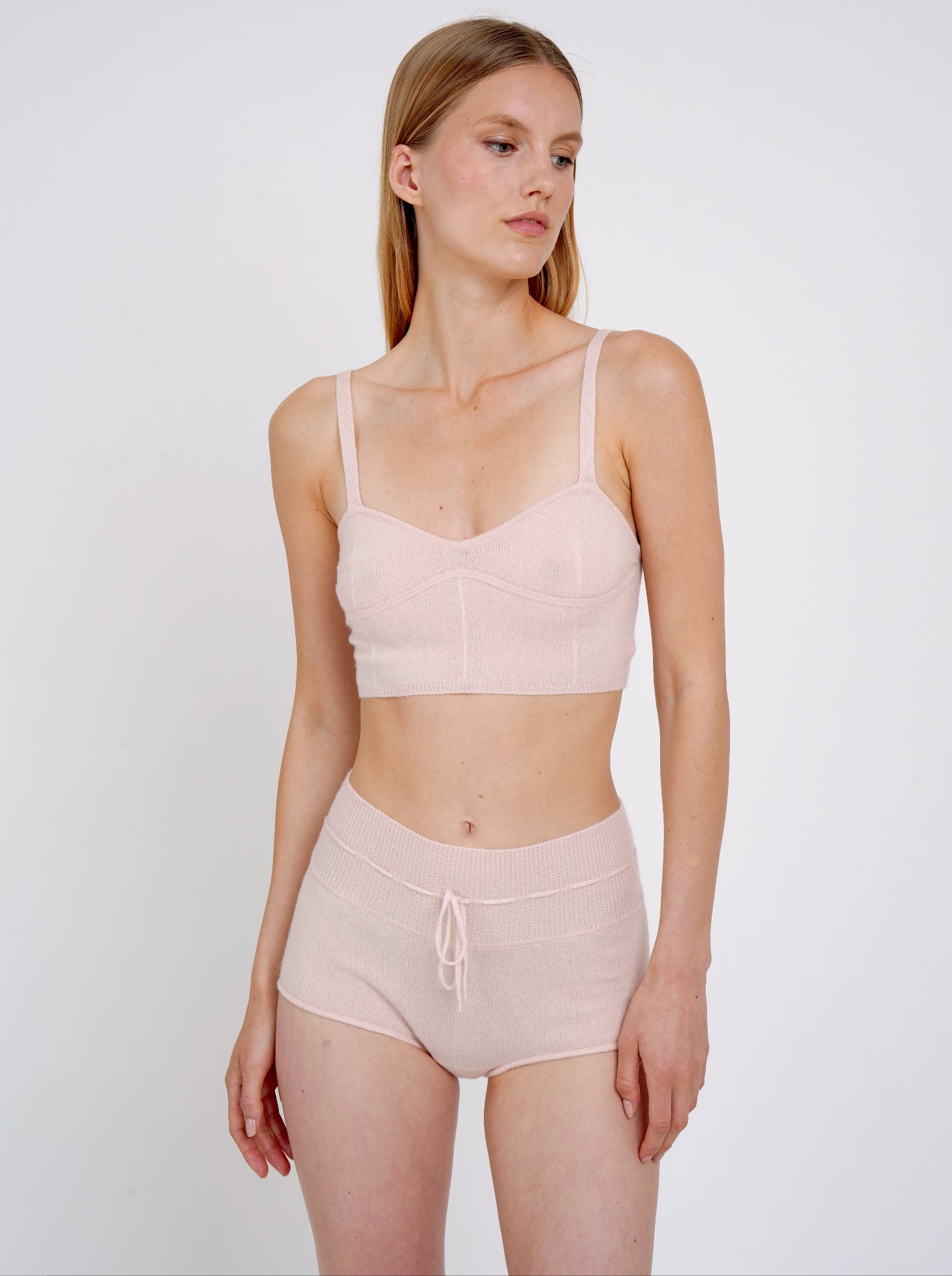 model wears pale peach knit cropped bra top and matching peach cashmere knit shorts with drawstring waist.