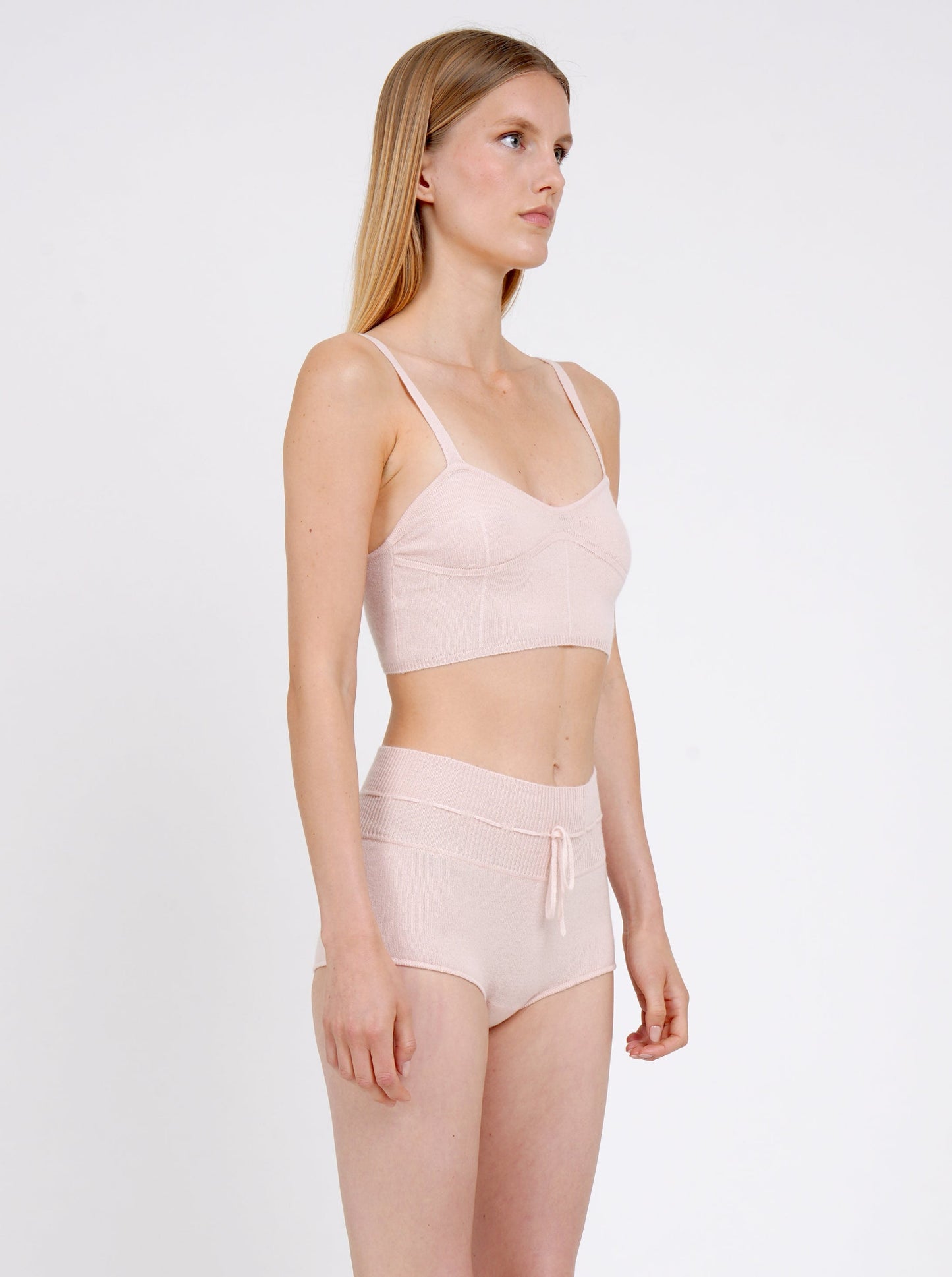 Side view close-up model in pale peach knit cropped bra top and matching peach cashmere knit shorts with drawstring waist.
