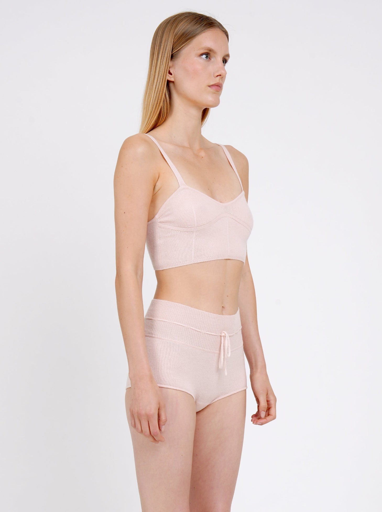 Side view close-up model in pale peach knit cropped bra top and matching peach cashmere knit shorts with drawstring waist.