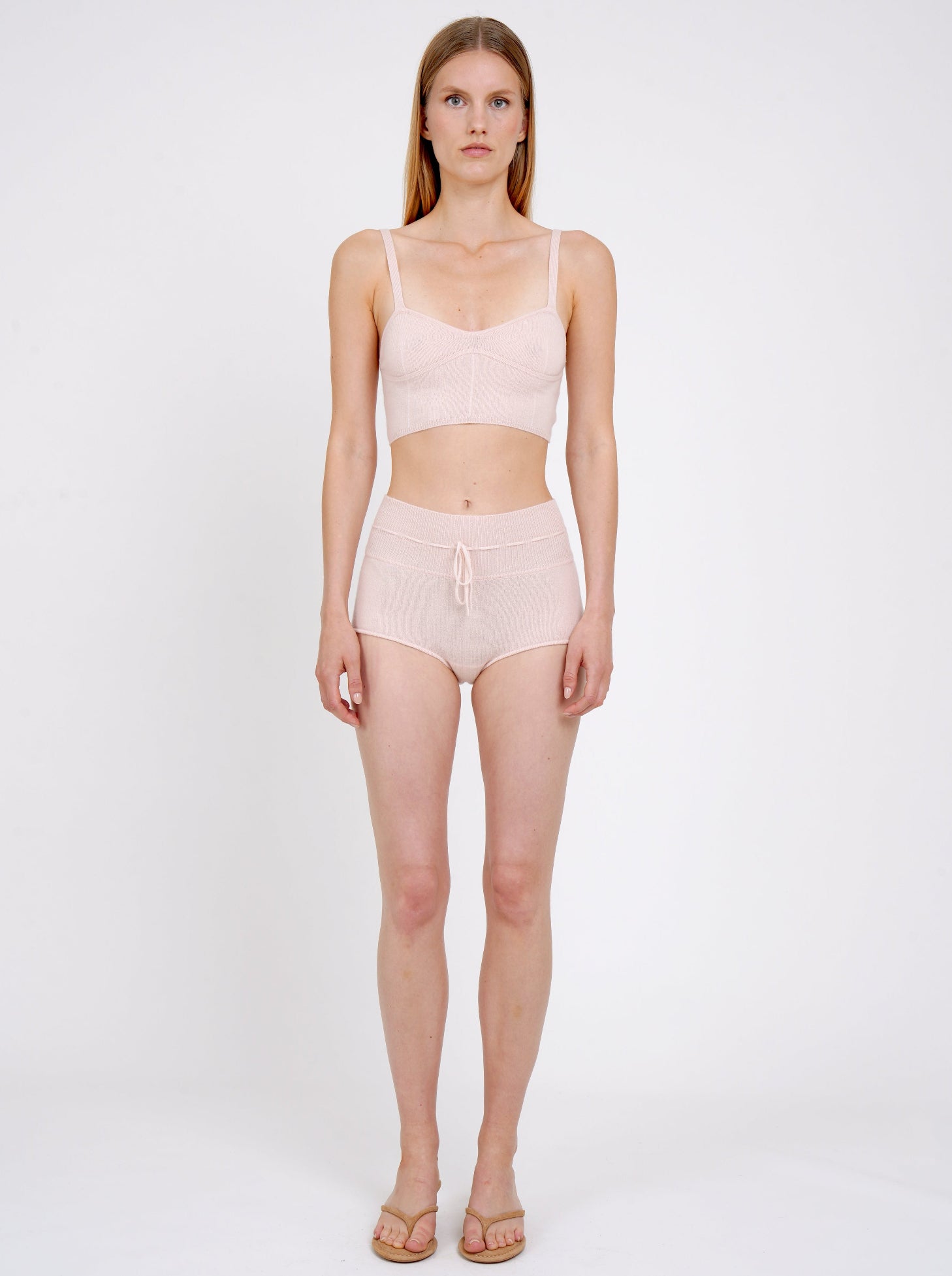 Front view model standing in pale peach knit cropped bra top and matching peach cashmere knit shorts with drawstring waist.