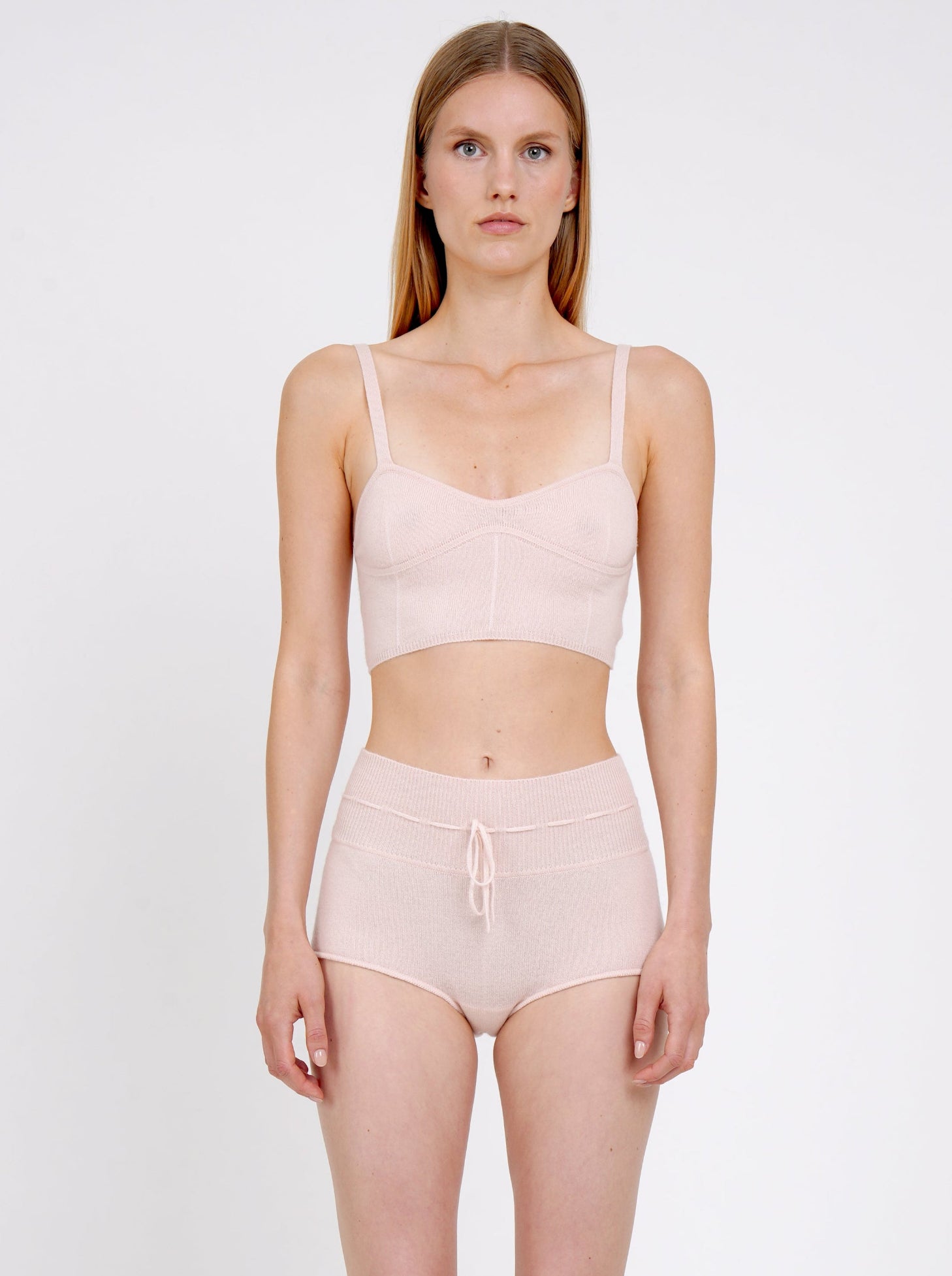 Front view model in pale peach cashmere shorts with drawstring waist and matching pale peach knit  cropped bra top.
