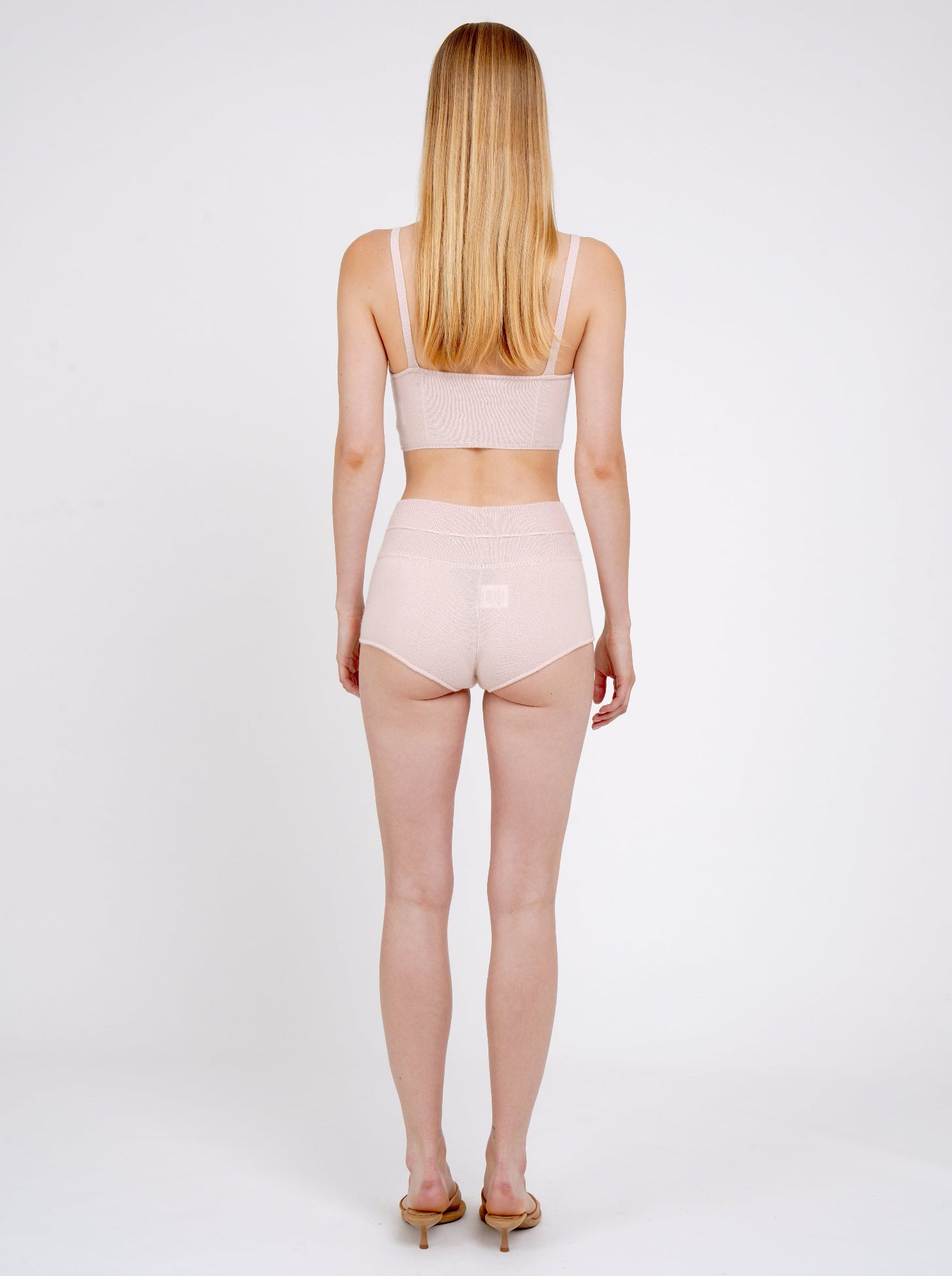 Back view model in pale peach cashmere shorts with drawstring waist and matching pale peach knit  cropped bra top.