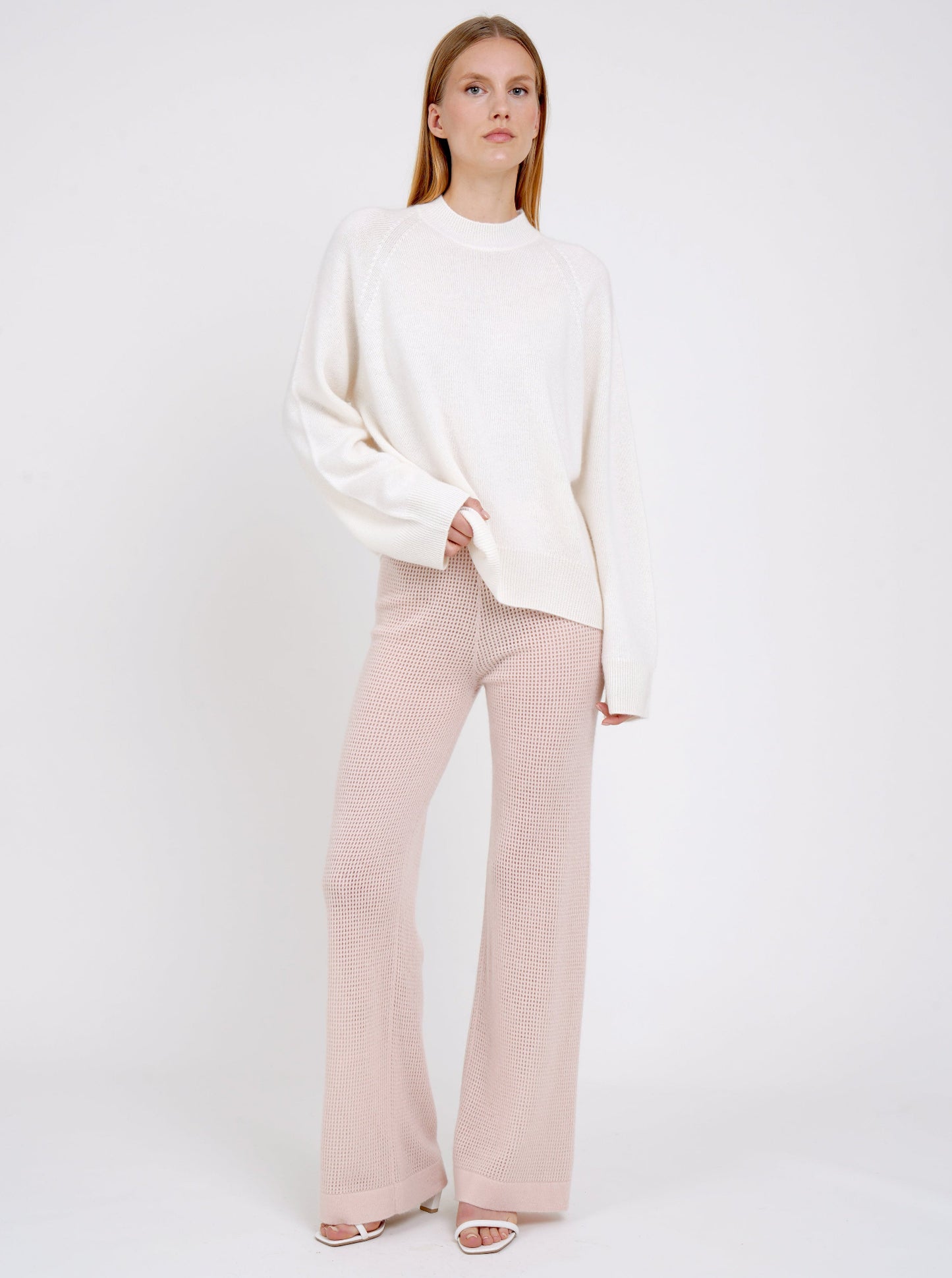 model wearing peach net knit wide leg trousers and a white long sweater