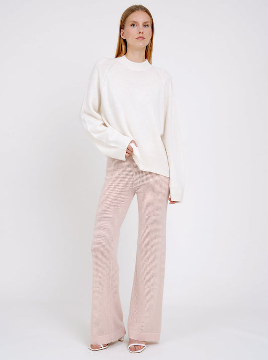 model wearing peach net knit wide leg trousers and a white long sweater