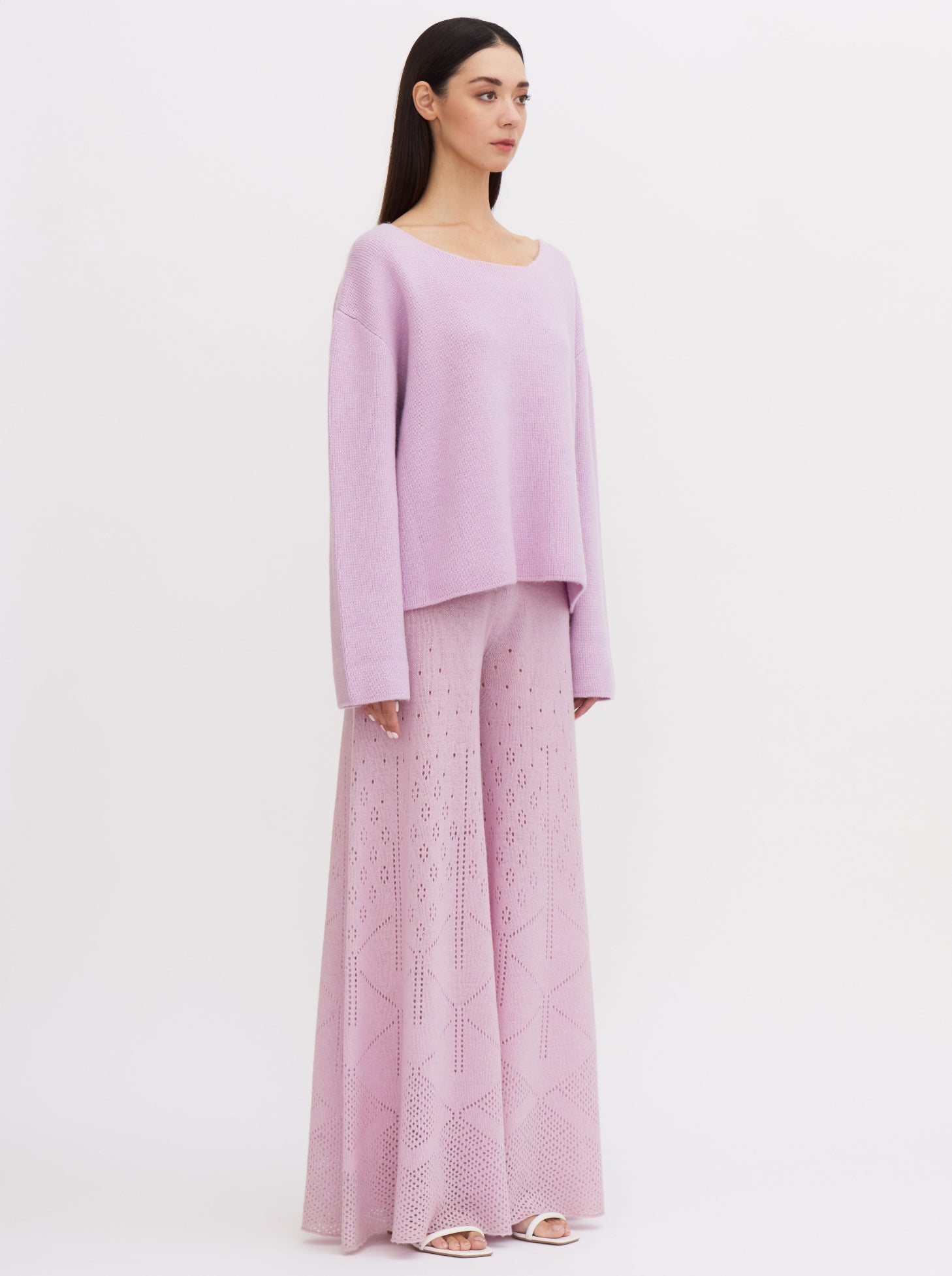 Model wearing a purple-pink cashmere jumper with a tie-back design, paired with wide-leg, embroidered cashmere trousers