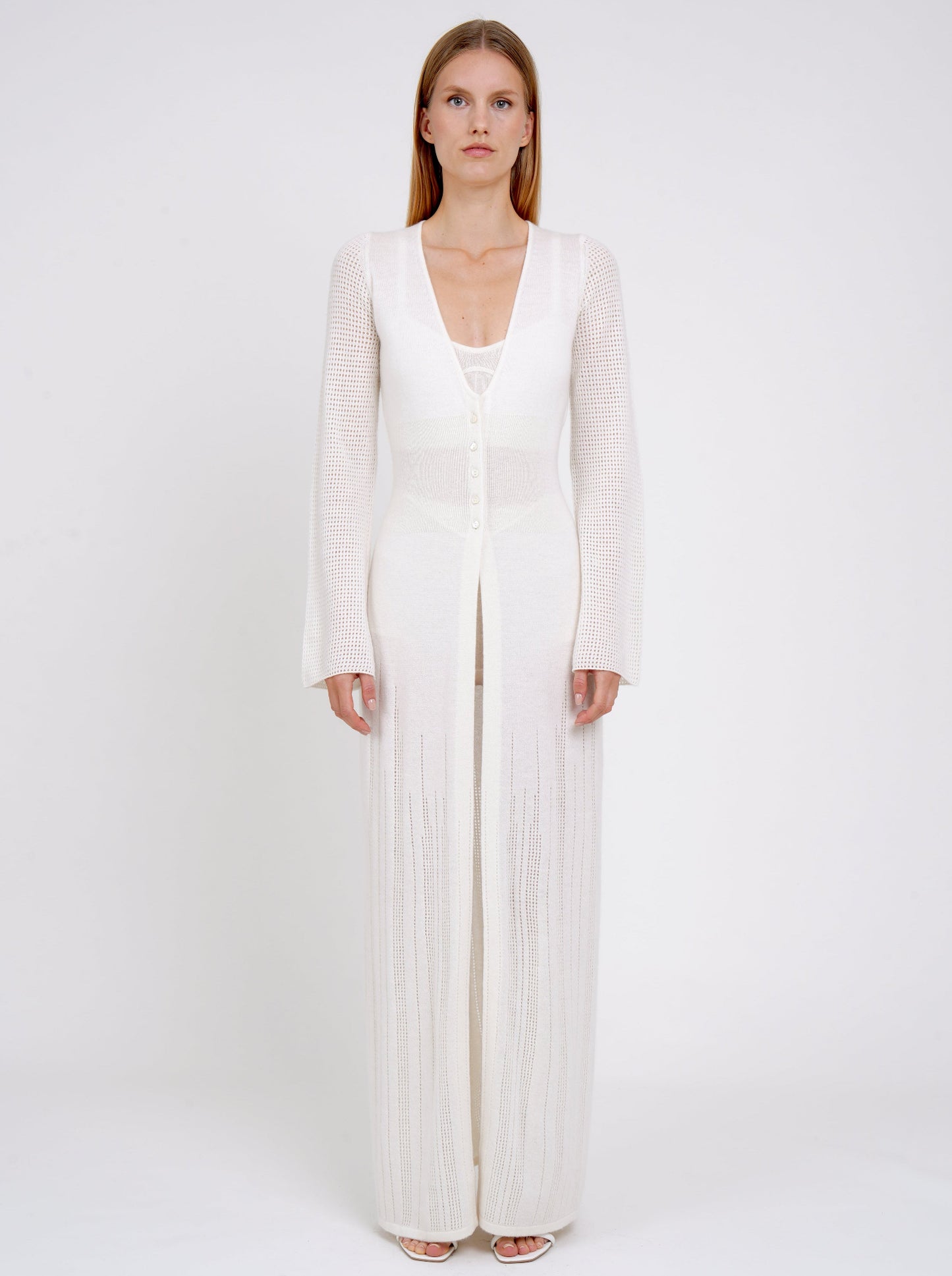 front view model in maxi-length long fitted light knit cashmere white cardigan with deep V neck, long sleeves, buttons through the waist. 