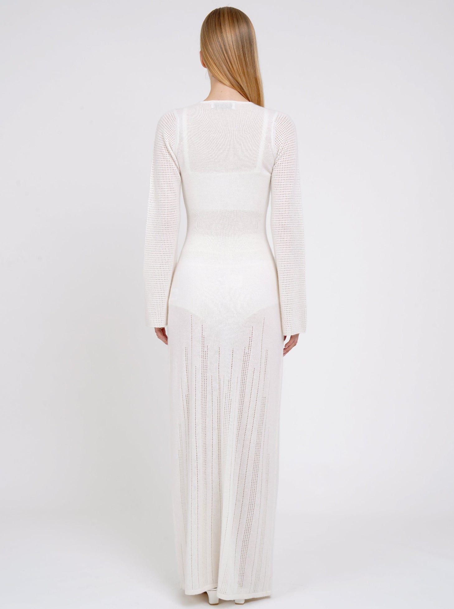 Back view model in maxi-length long fitted light knit cashmere white cardigan with deep V neck, long sleeves, buttons through the waist. 