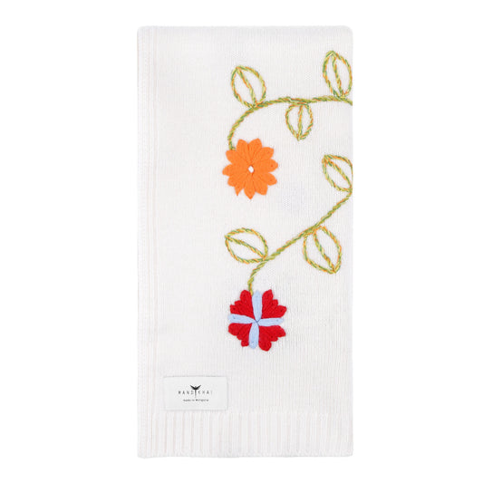 White knitted cashmere, square, baby cot blanket with a brightly coloured hand embroidery of flowers and leaves.