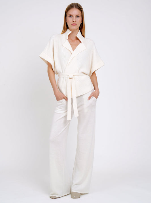 model wears white ribbed knit cashmere belted jacket with wide short sleeves and white knit pants.