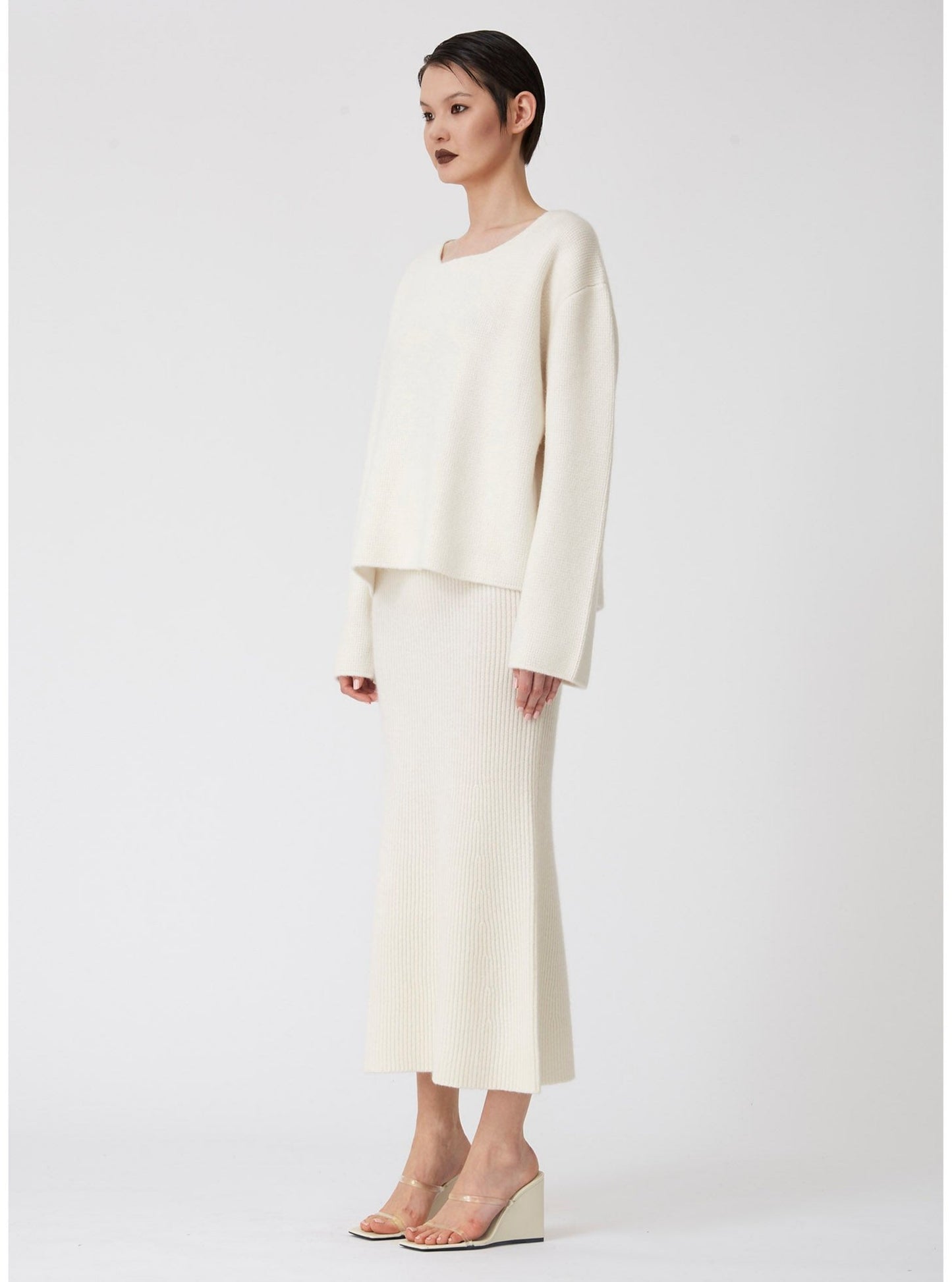 Modal sideview showing midi length white ribbed knit flared skirt with boxy white cashmere long sleeve jumper.