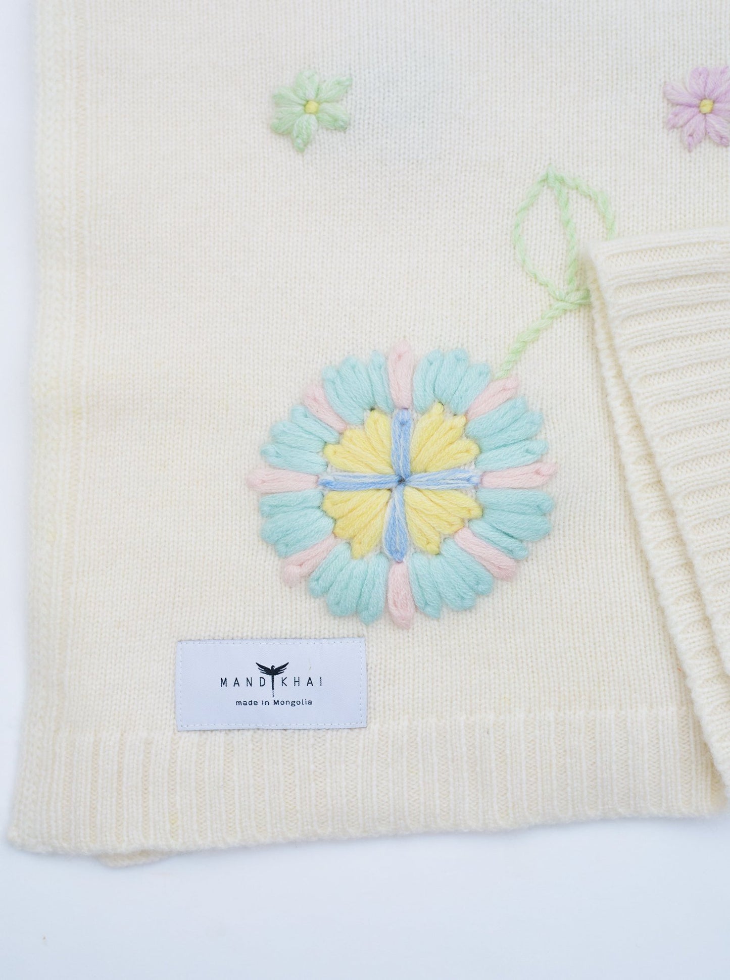 Close up Flat Lay of the White Hand Embroidered Cashmere Baby Blanket with pastel multi colour flower 