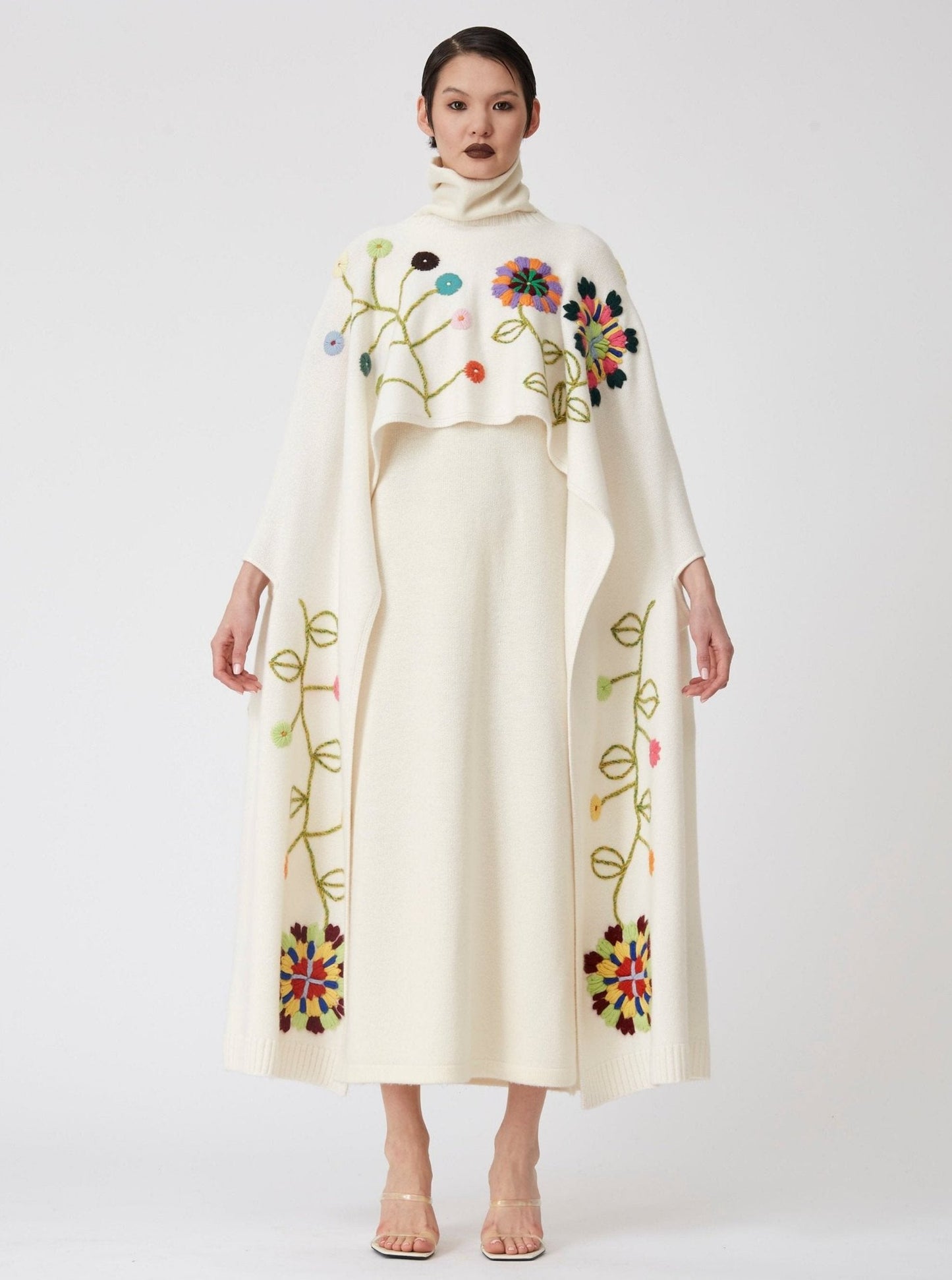 Model wearing a White Hand Embroidered Cashmere long Poncho with flowers over a white cashmere dress 