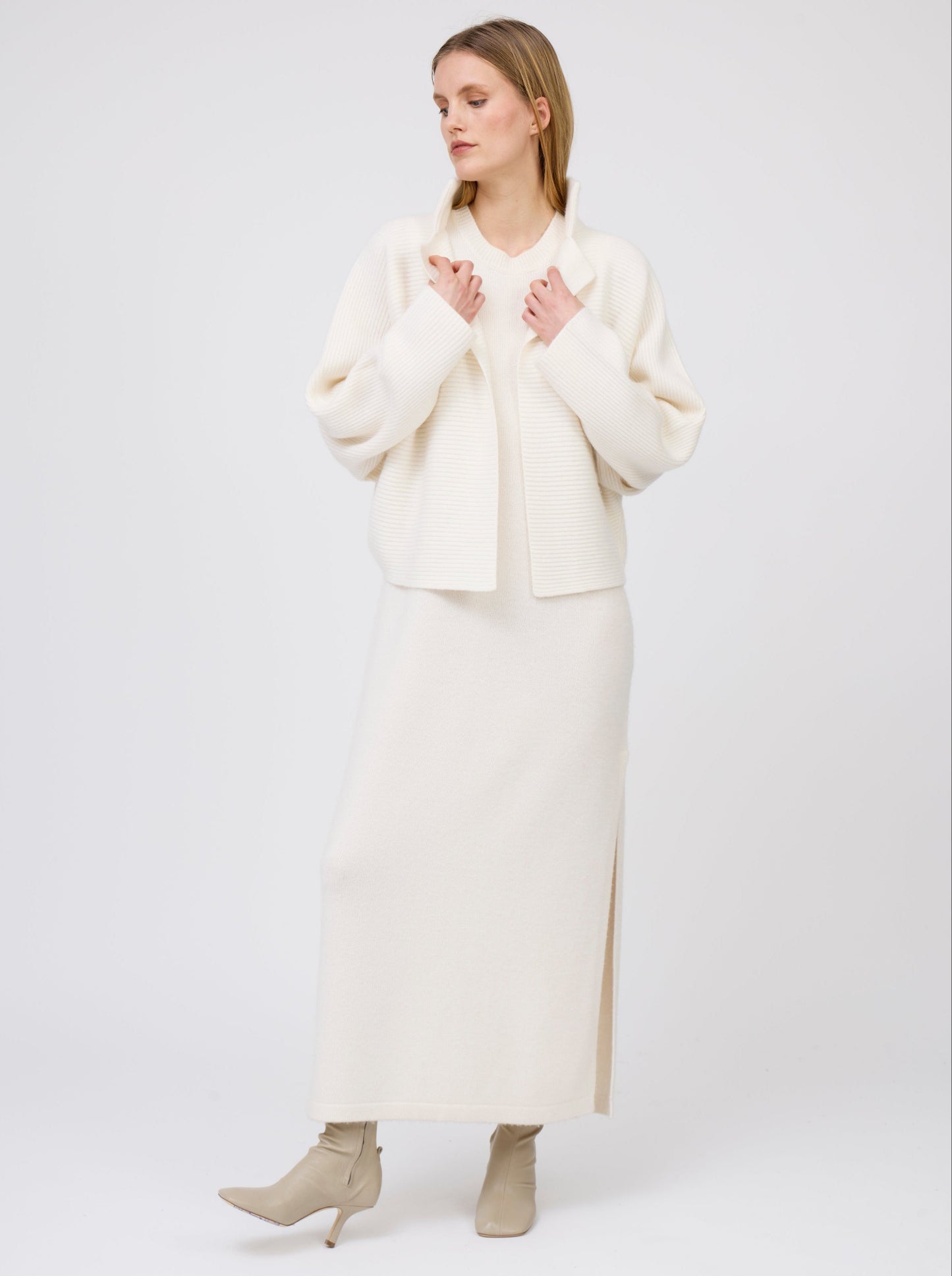 Model wears relaxed fit white ribbed knit cashmere short jacket with collar and kimono sleeves, worn with long straight white cashmere knit dress.