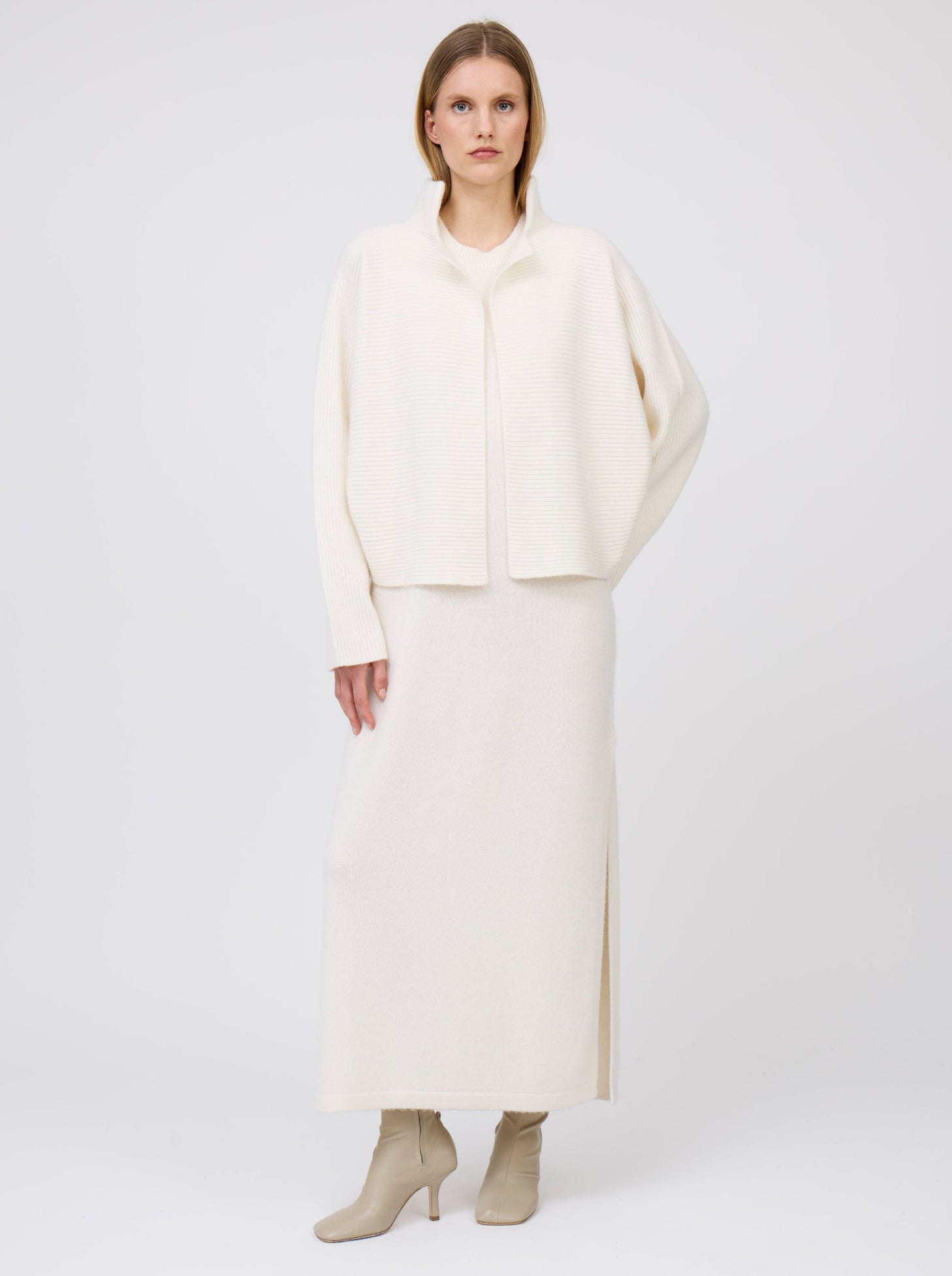 standing model in ribbed knit white cashmere short jacket with collar and kimono sleeves, worn with long white cashmere knit dress.