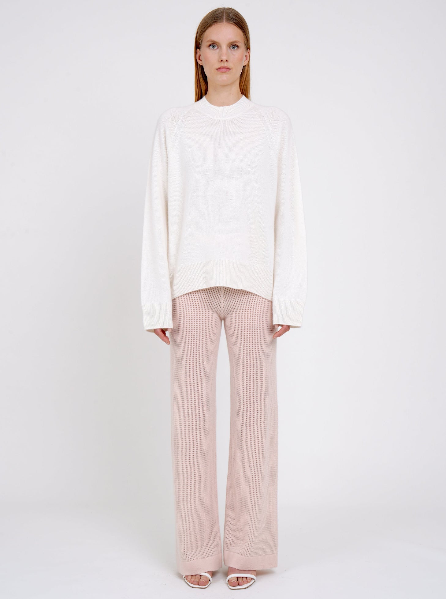 Front view model in white cashmere jumper with round neck, long sleeves and pale peach pink knit cashmere pants.