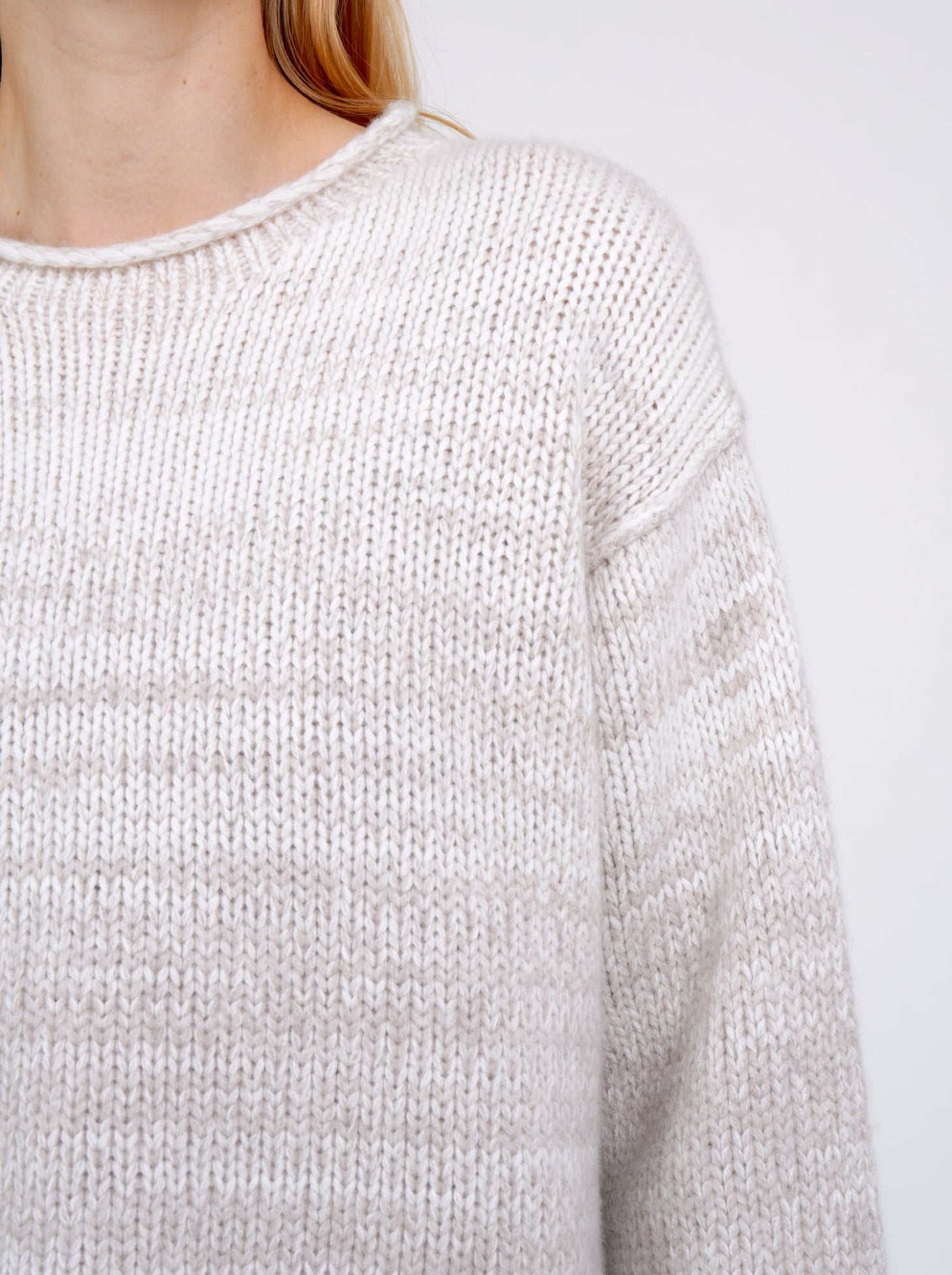 Close-up crop detail mixed colour knitted jumper in natural white and beige, with round neck.