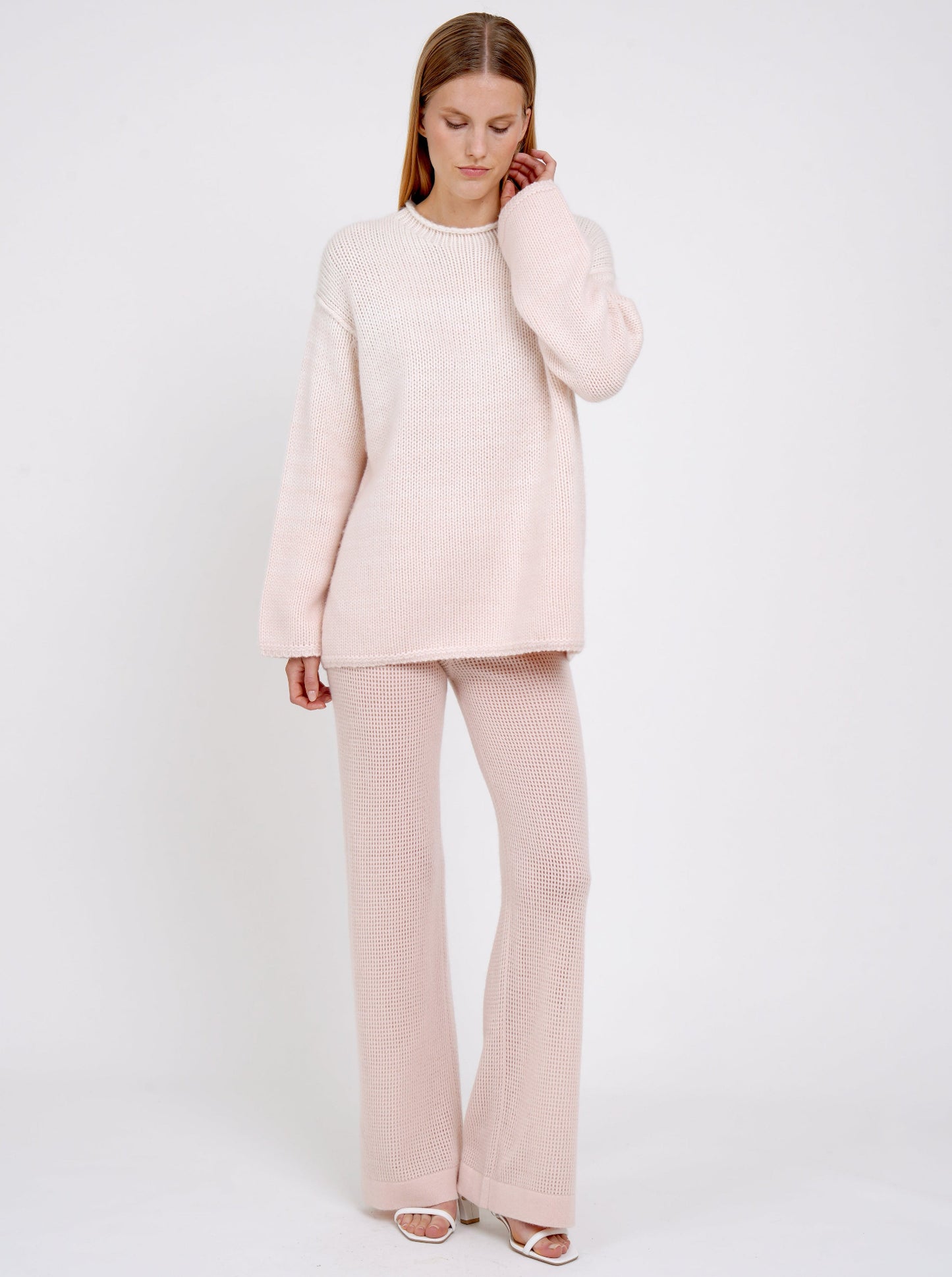 model wears relaxed fit mixed colour chunky knit jumper in peach and white with peach net knit wide leg pants.