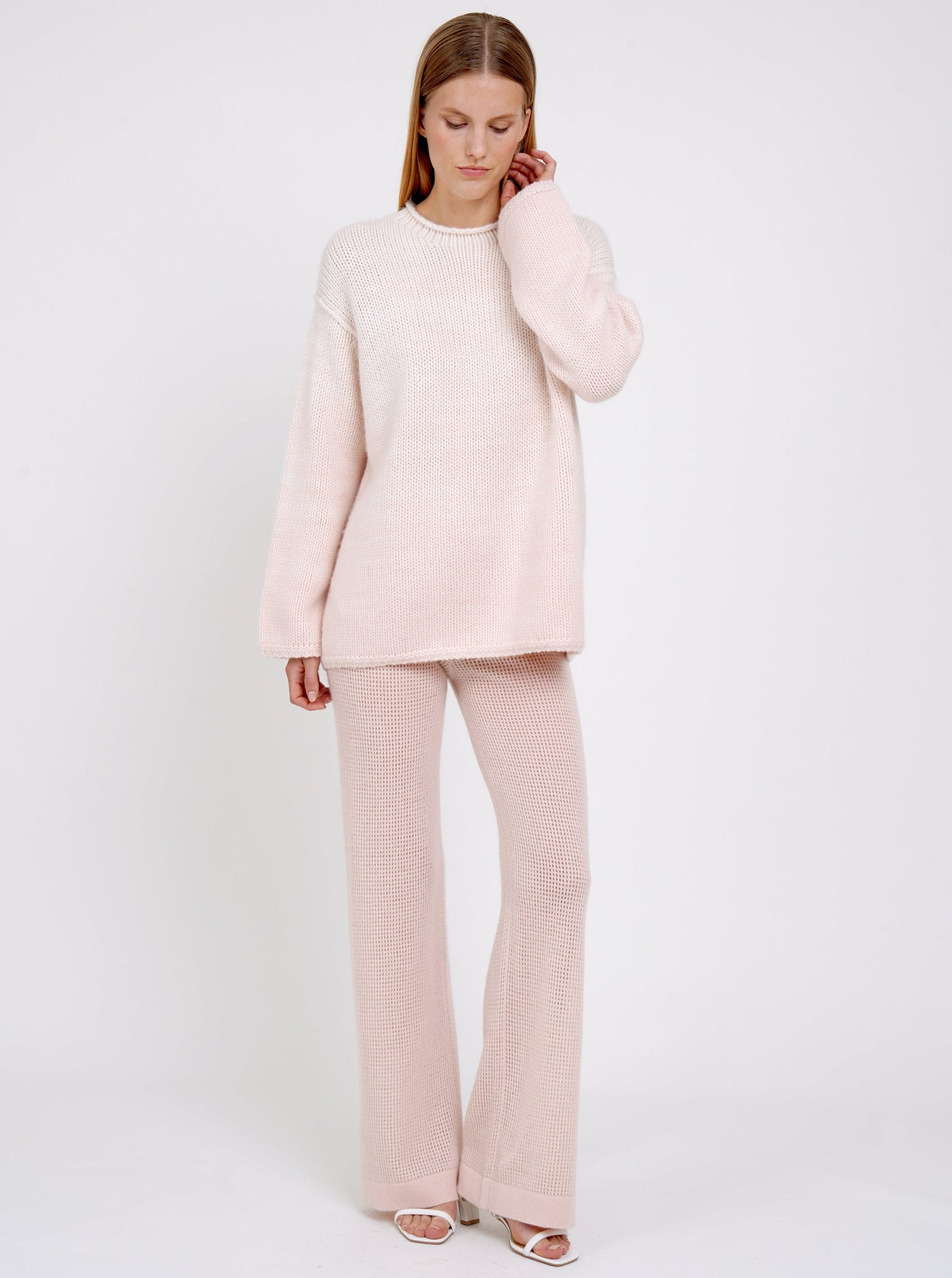 model wears relaxed fit mixed colour chunky knit jumper in peach and white with peach net knit wide leg pants.