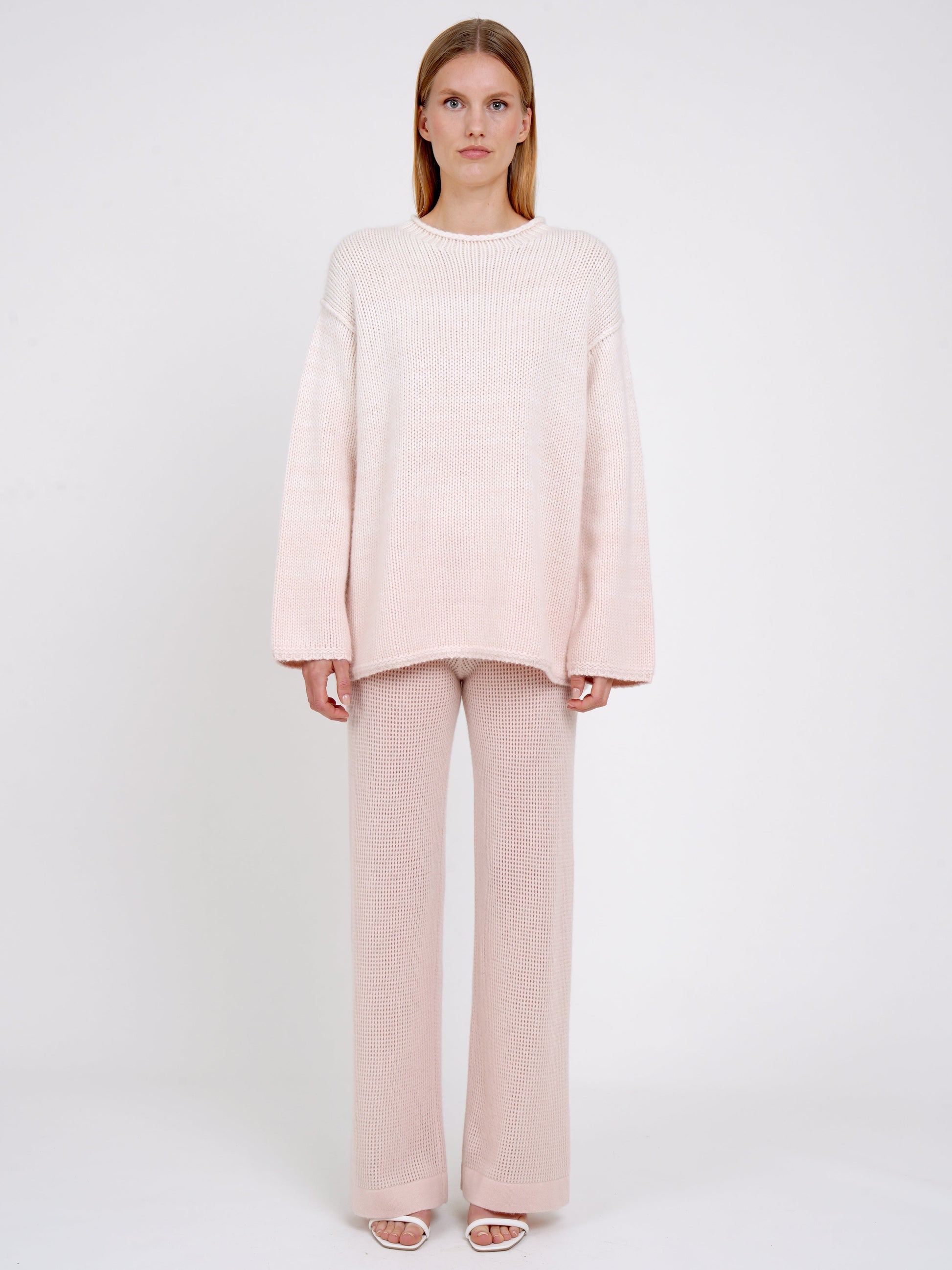 front view model in relaxed fit mixed colour chunky knit jumper in peach and white with peach net knit wide leg pants.
