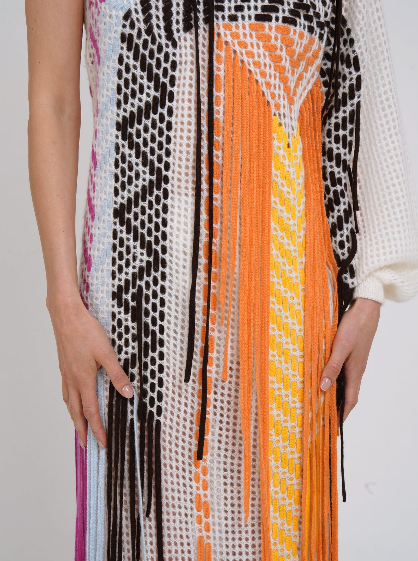 cropped detail of white light weight cashmere shift dress decorated with woven coloured fringes.