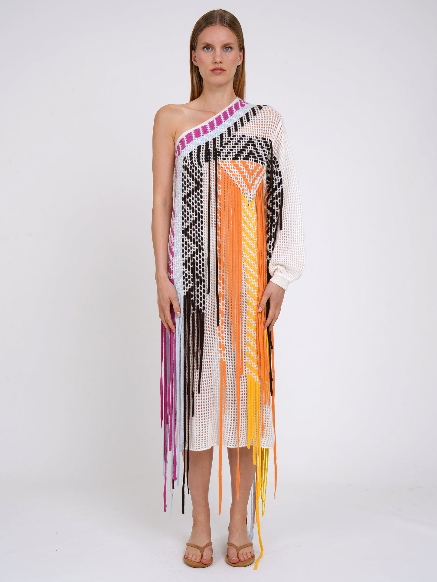 Front view white summer weight cashmere one shoulder shift dress with asymmetric neckline, decorated with coloured fringes which fall to the ground.