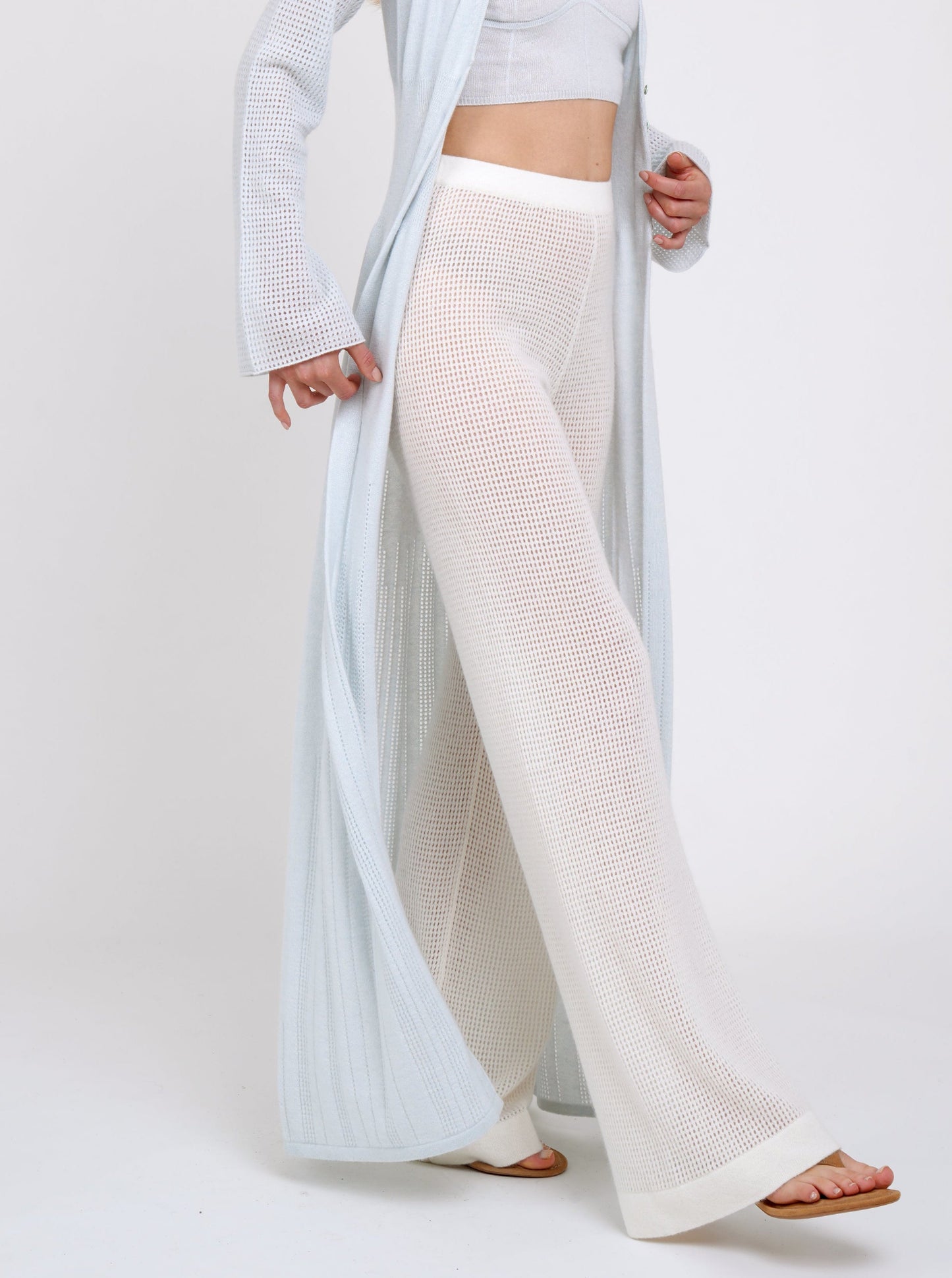 Model wearing white net knit cashmere pants with mules and long pale blue cardigan 