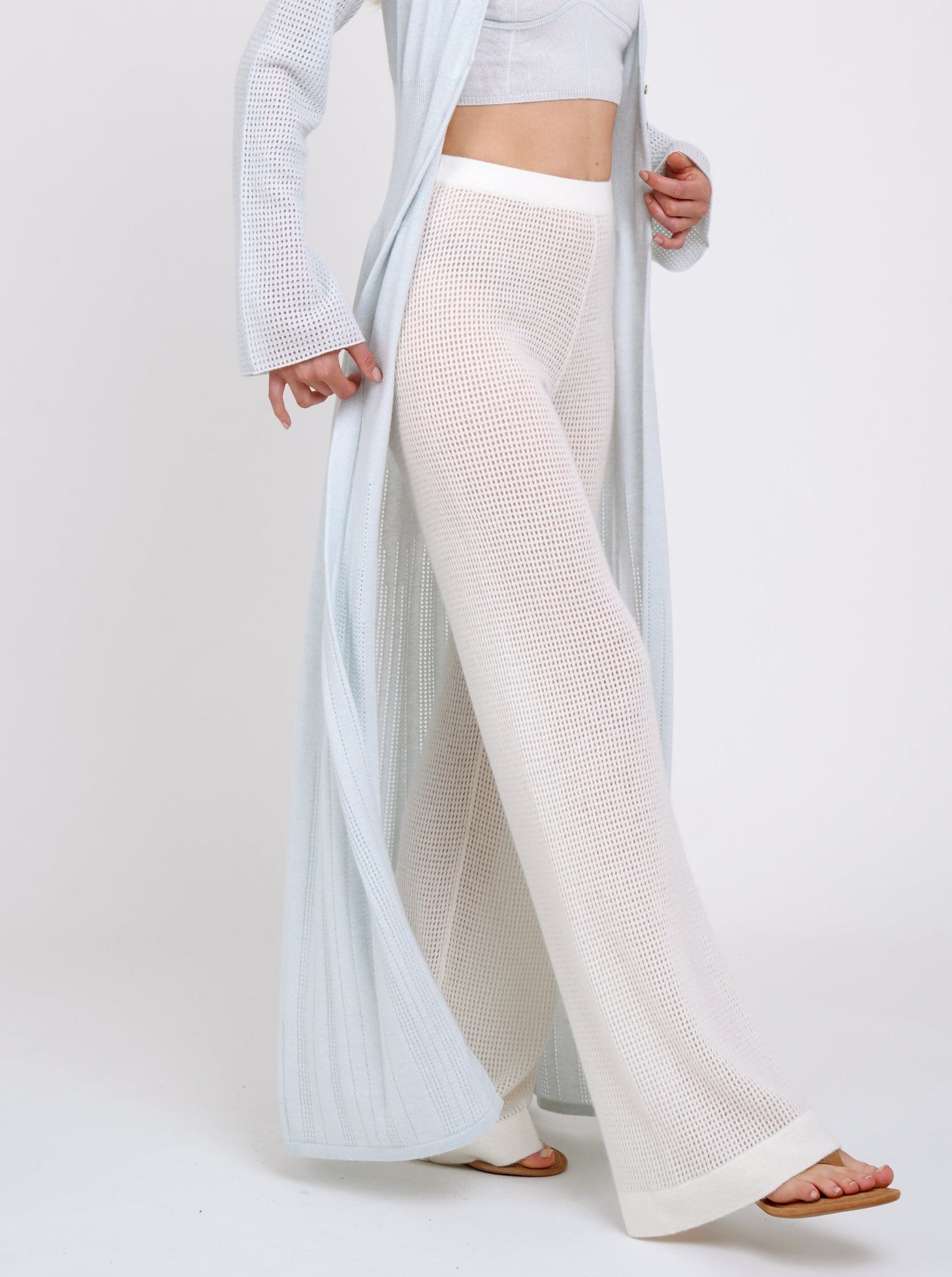 Model wearing white net knit cashmere pants with mules and long pale blue cardigan 