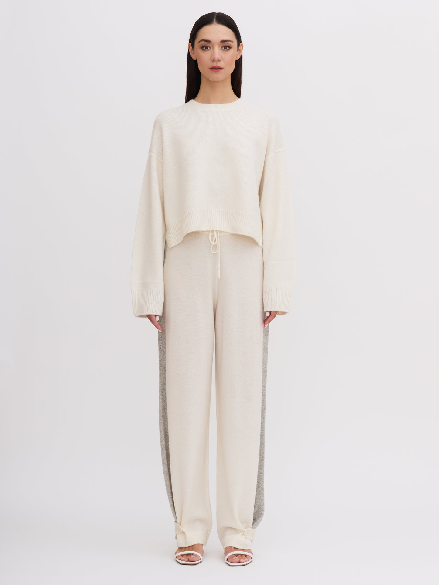 Front view of model wearing white cropped length round neck cashmere jumper with white wide leg pants.