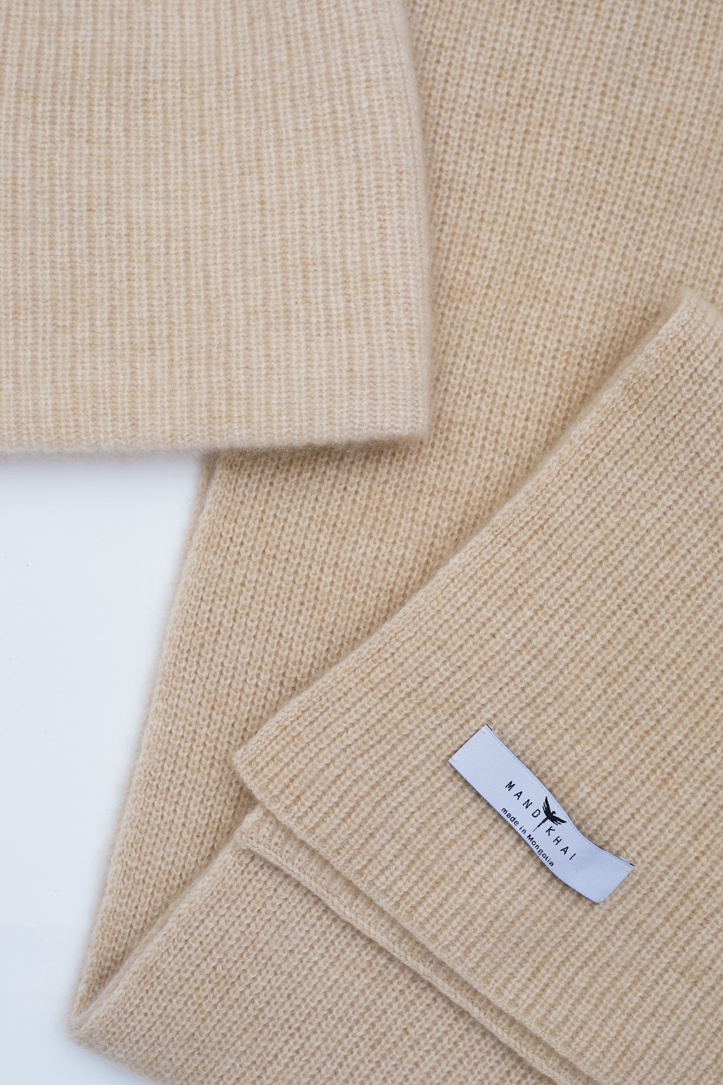 flat lay close up of beige cashmere ribbed knit scarf and hat set with mandkhai label detail 