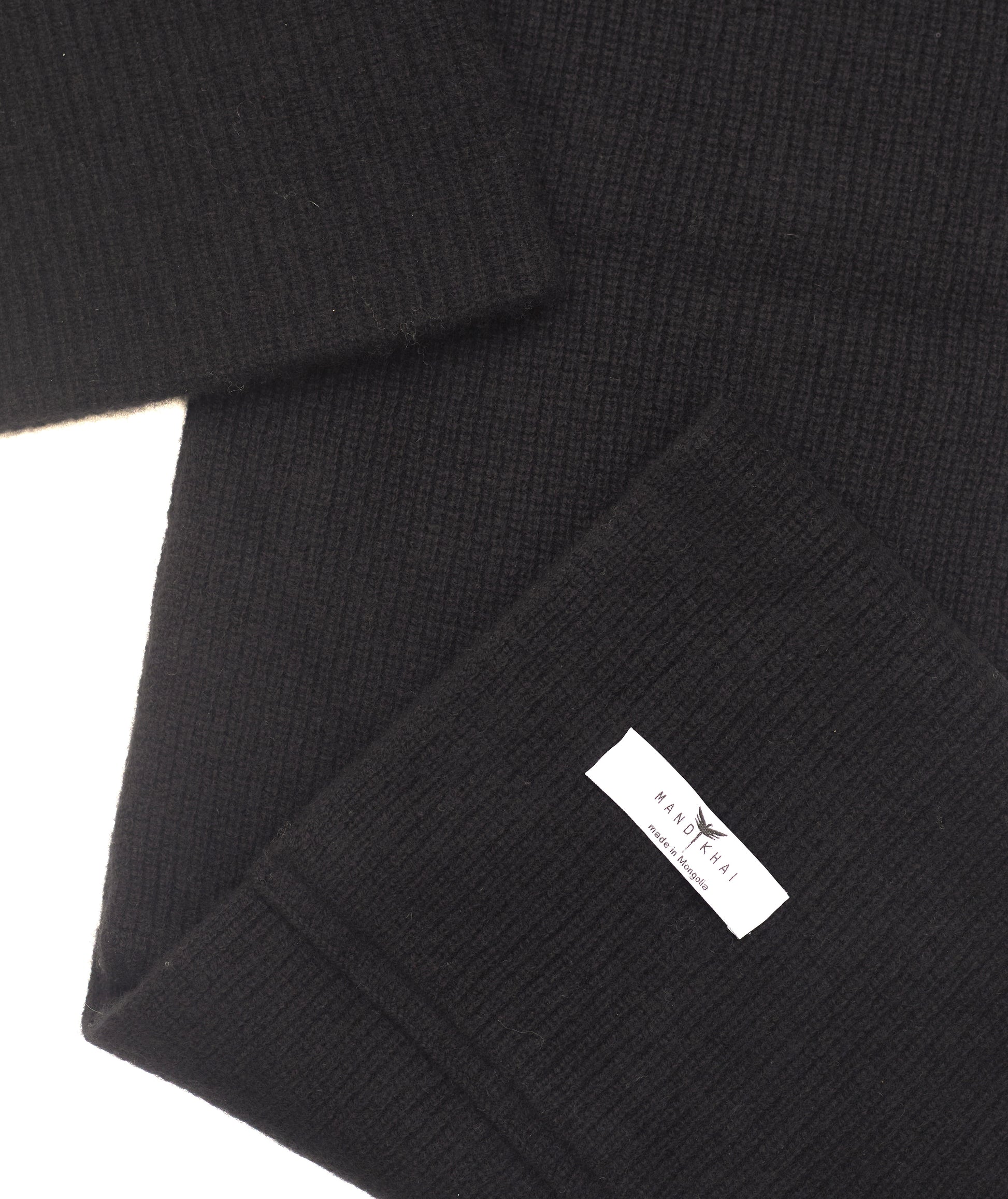 flat lay close up of black cashmere ribbed knit scarf and hat set with mandkhai label detail 