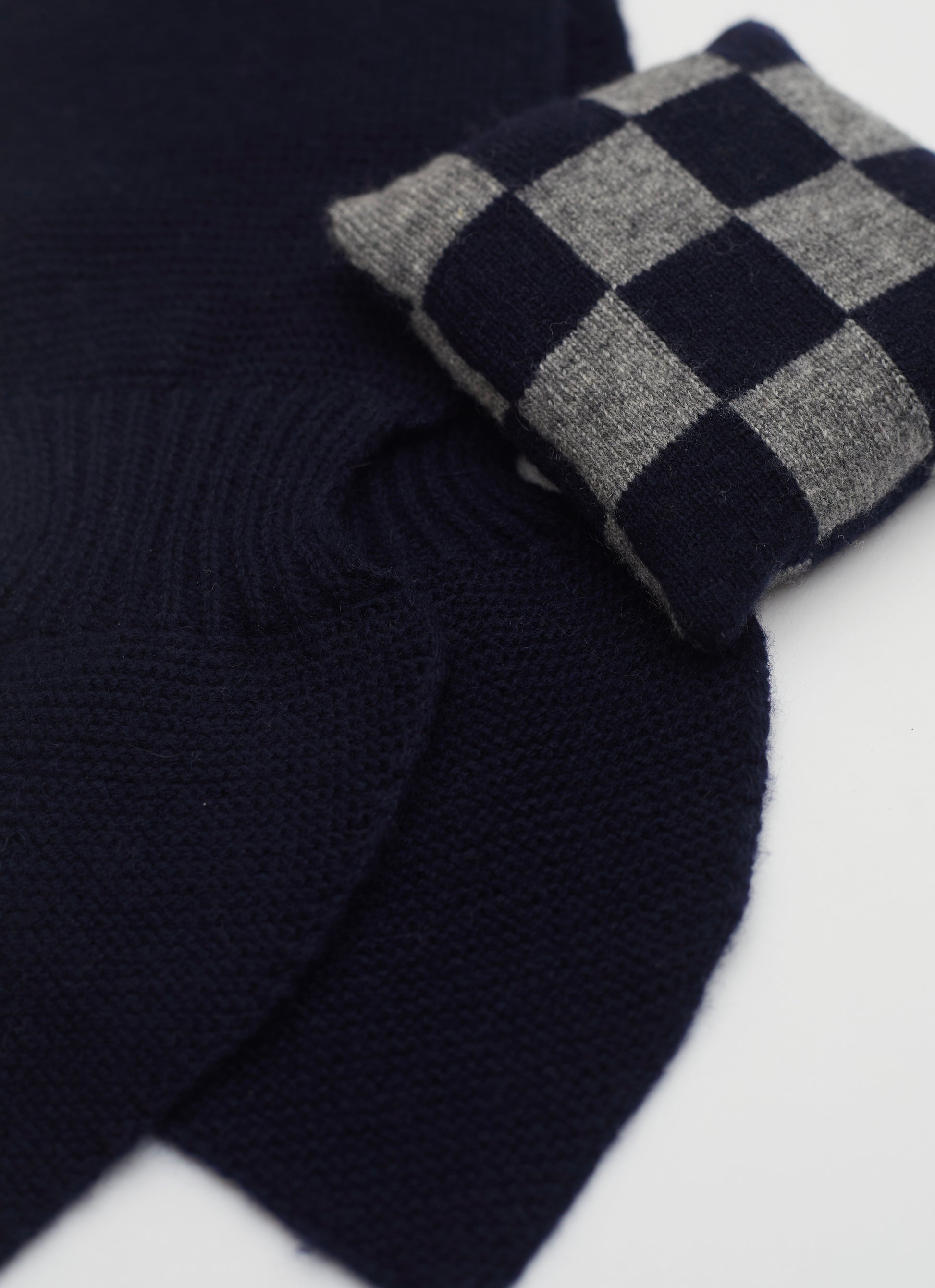 Close up flat lay of dark navy cashmere neck scarf and dark navy and grey checked mini lavender cushion set 