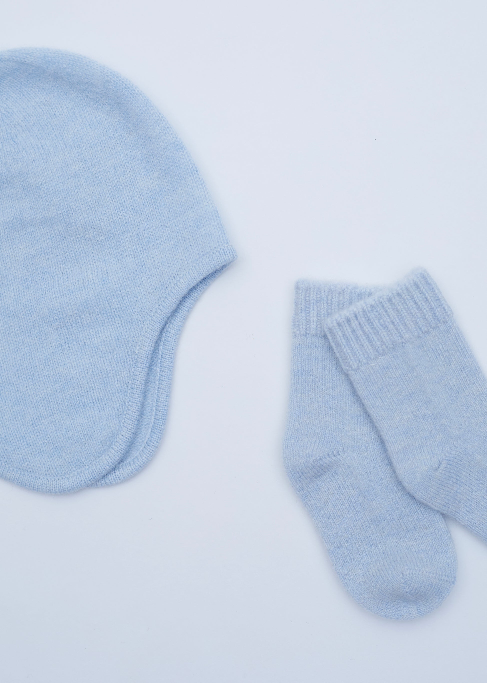 close up flat lay of the light blue cashmere baby hat and socks set 