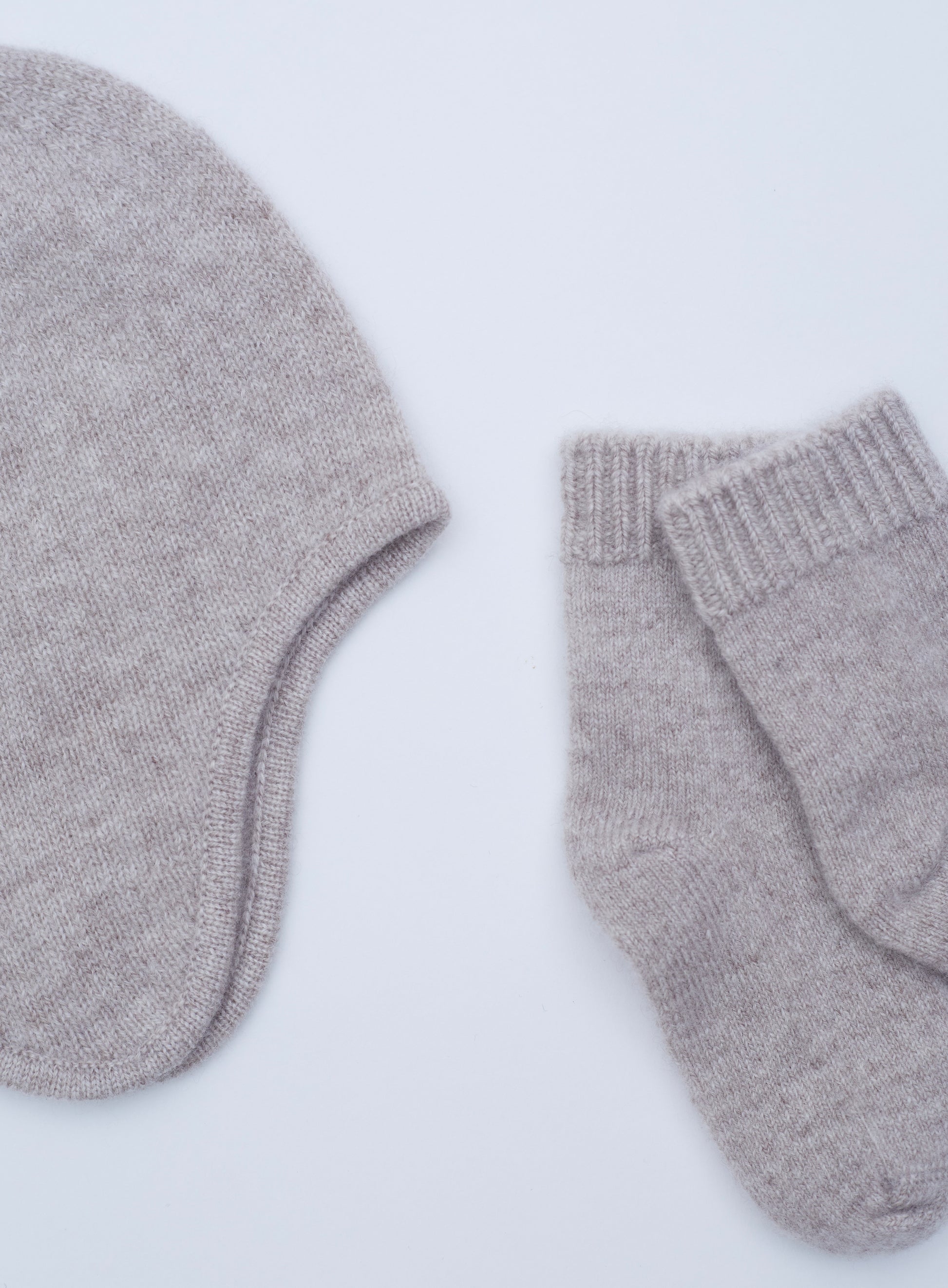 close up flat lay of the light brown cashmere baby hat and socks set