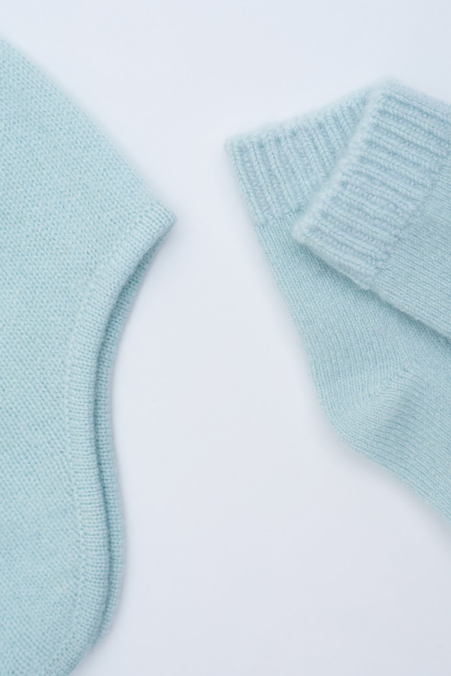 close up flat lay of the mint green cashmere baby hat and socks set 