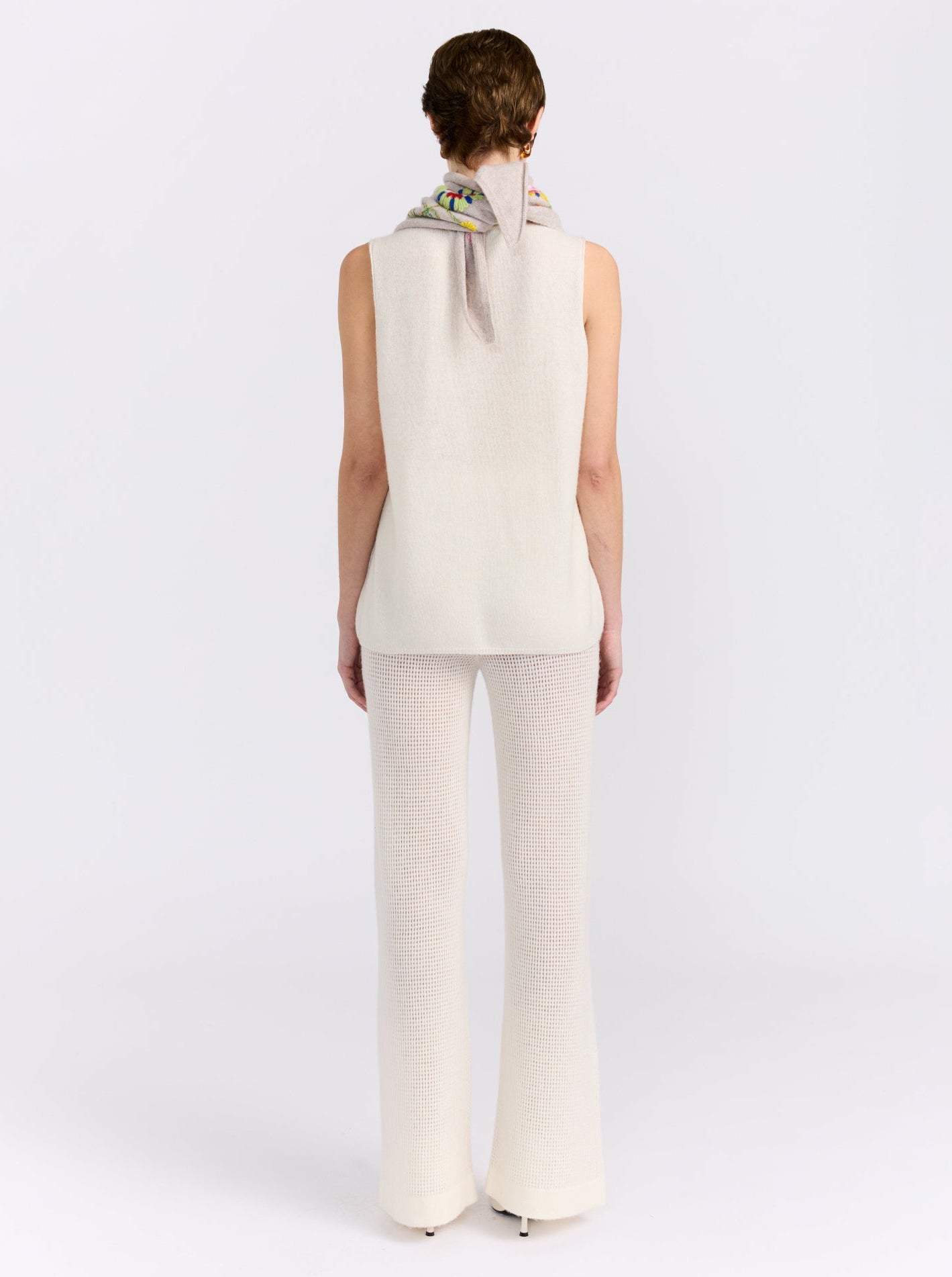 Model wearing the MANDKHAI New Beige embroidered triangle cashmere scarf styled around the neck.