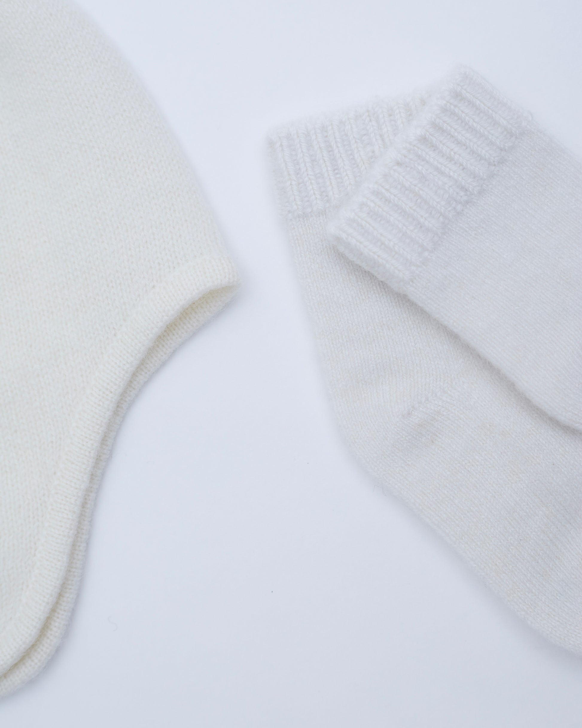 close up flat lay of the white cashmere baby hat and socks set 